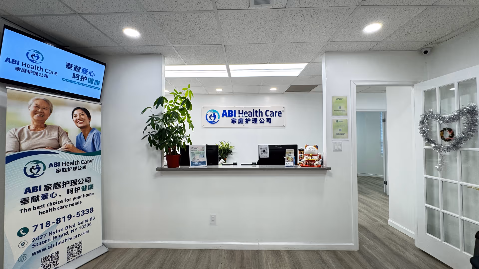 Reception area with ABI Health Care sign, desk, plants, and doorway.