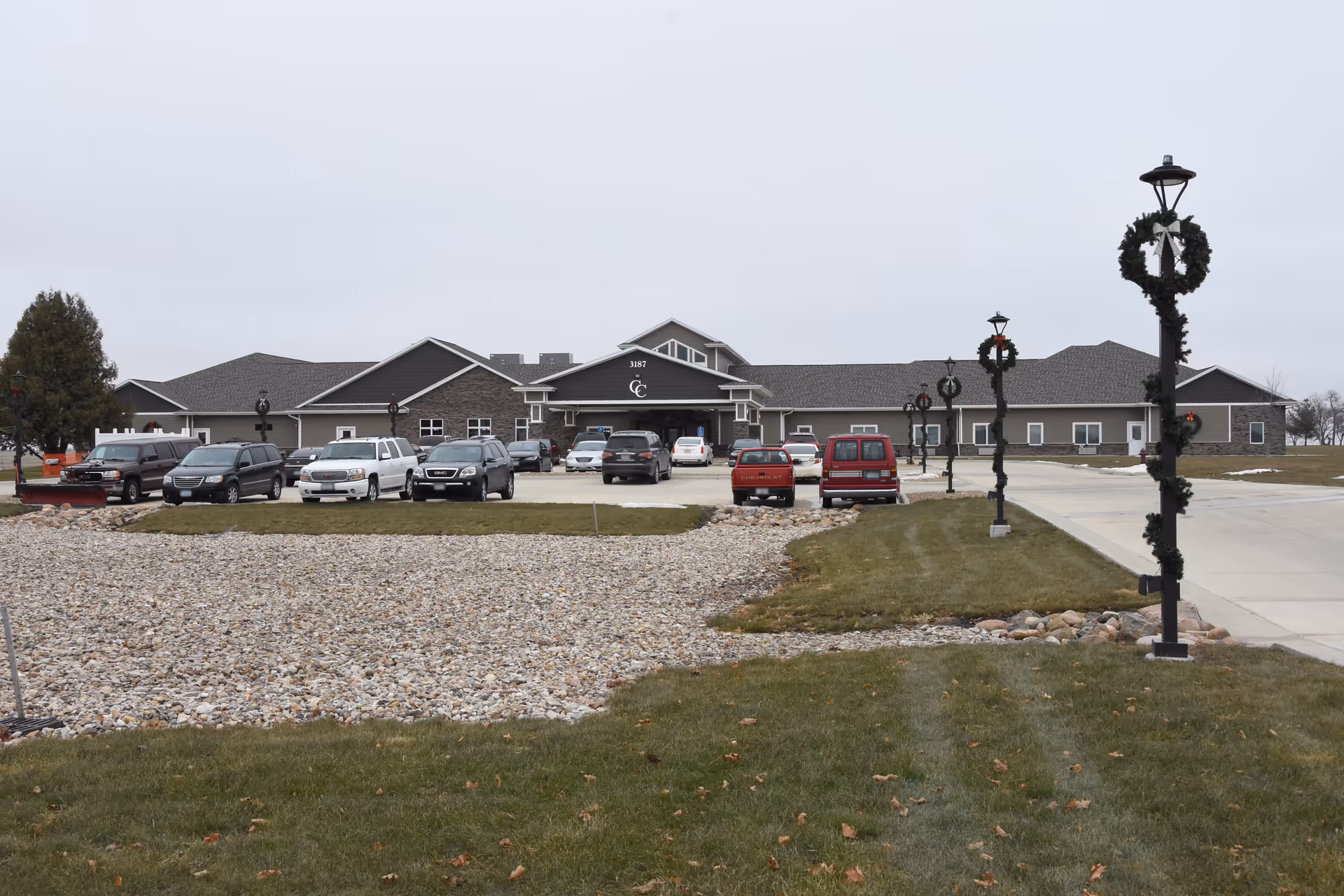 Front view of Cobblestone Court Assisted Living with parked cars and decorative lampposts.