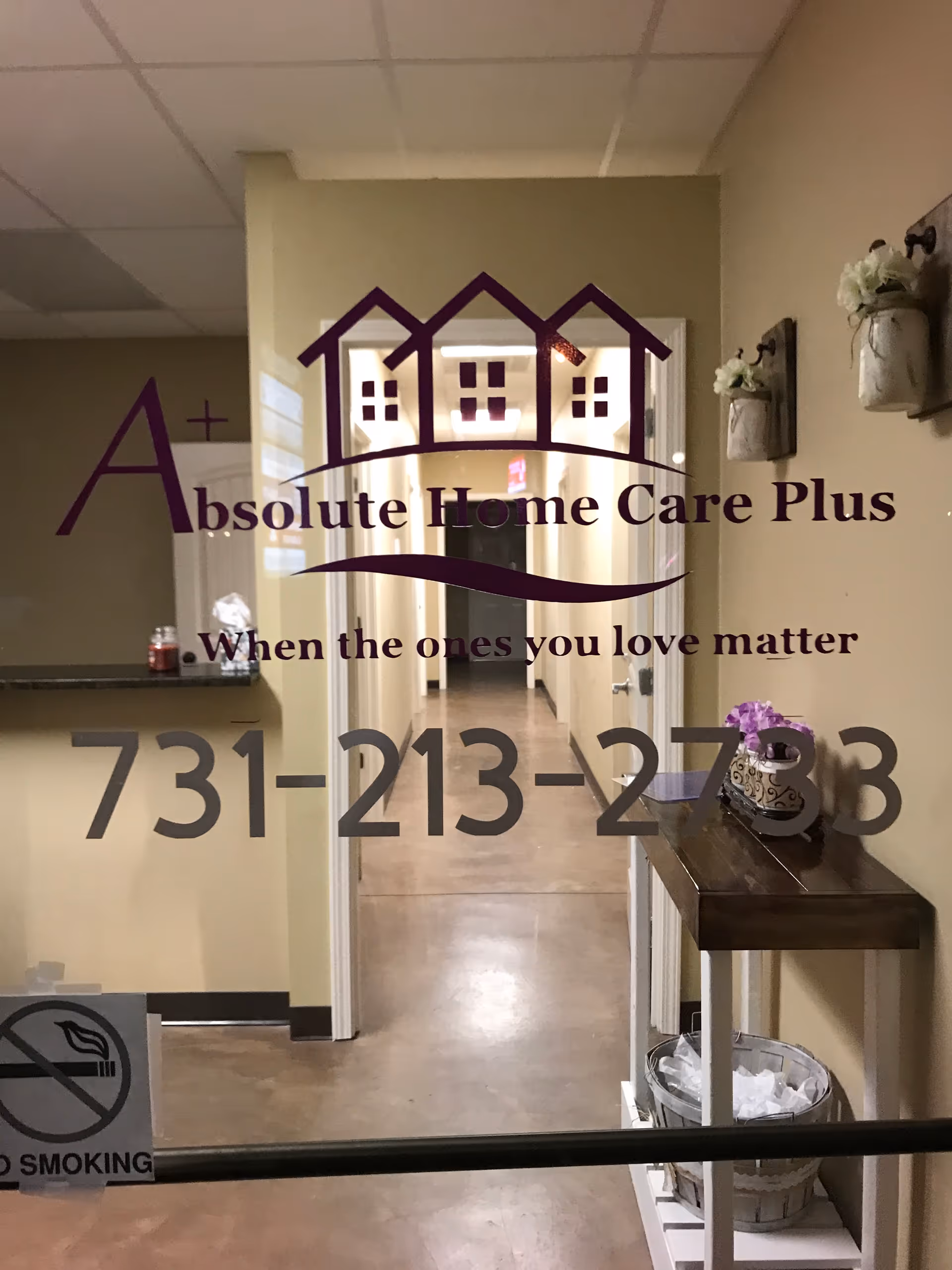Glass door with Absolute Home Care Plus logo; hallway visible beyond.