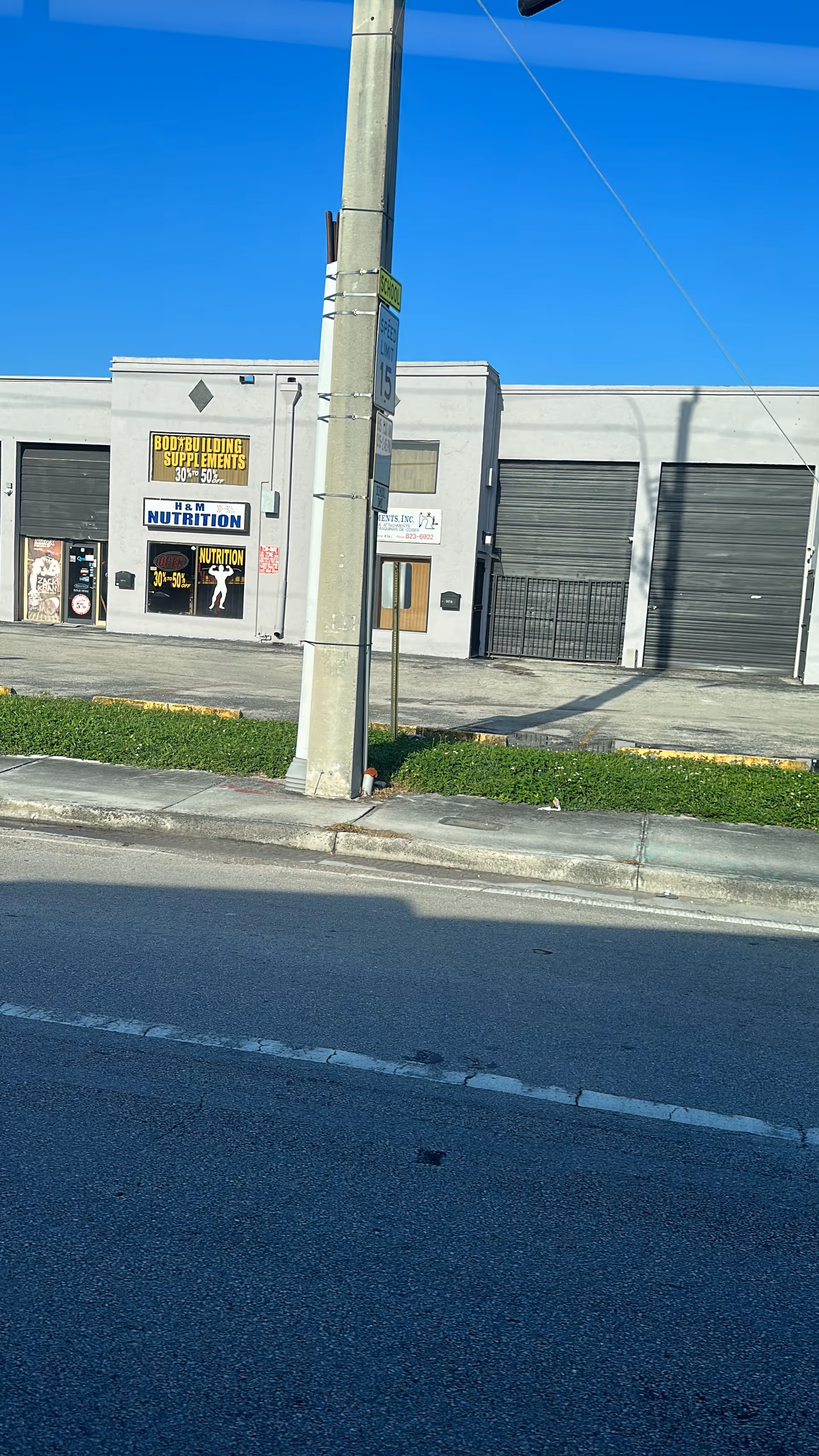 Exterior view of a gray building with multiple garage doors and storefront signs.