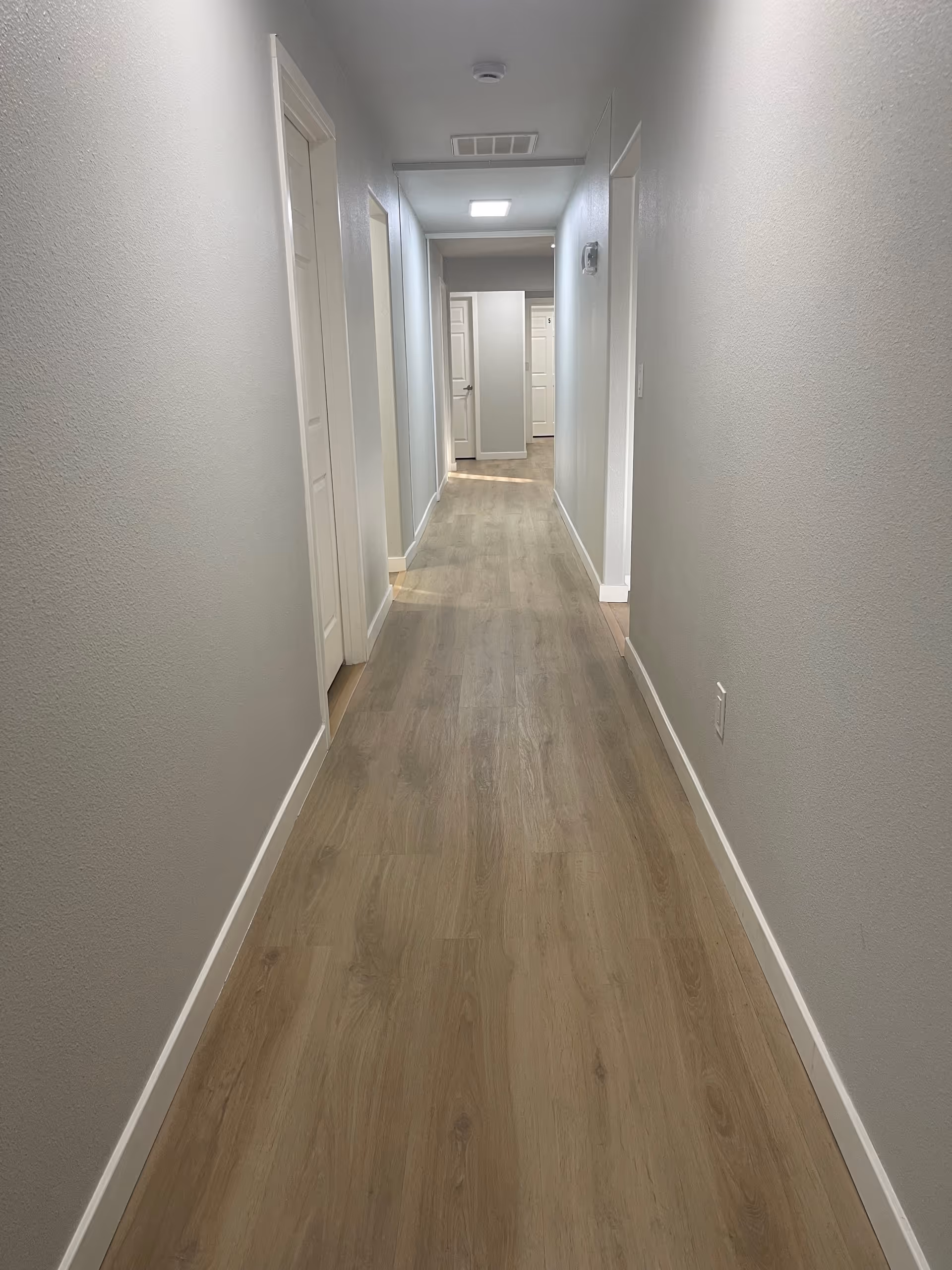 A long, empty hallway in a senior living facility with doors on both sides