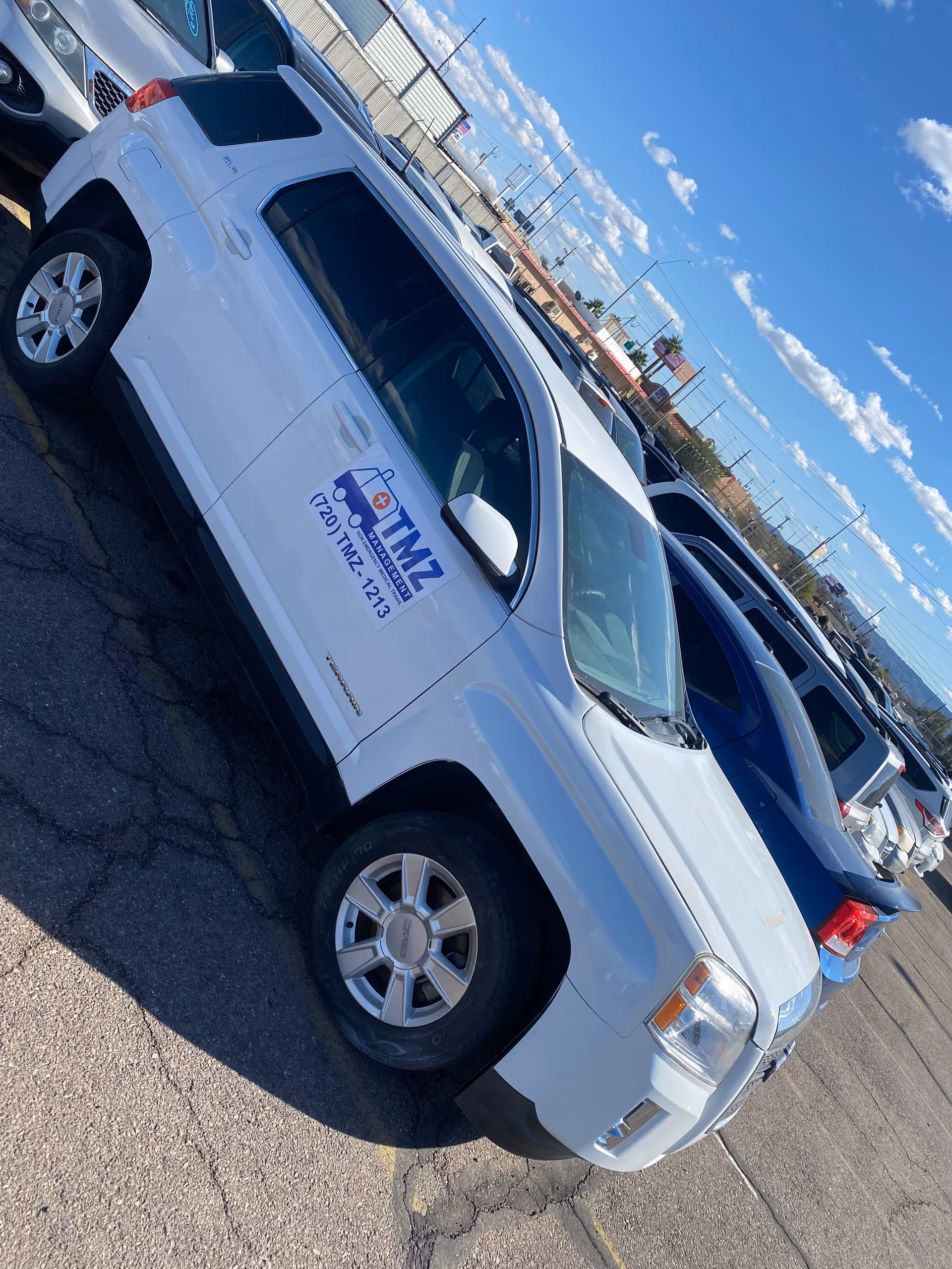 White TMZ Medical Transportation van parked in a lot beside other vehicles.
