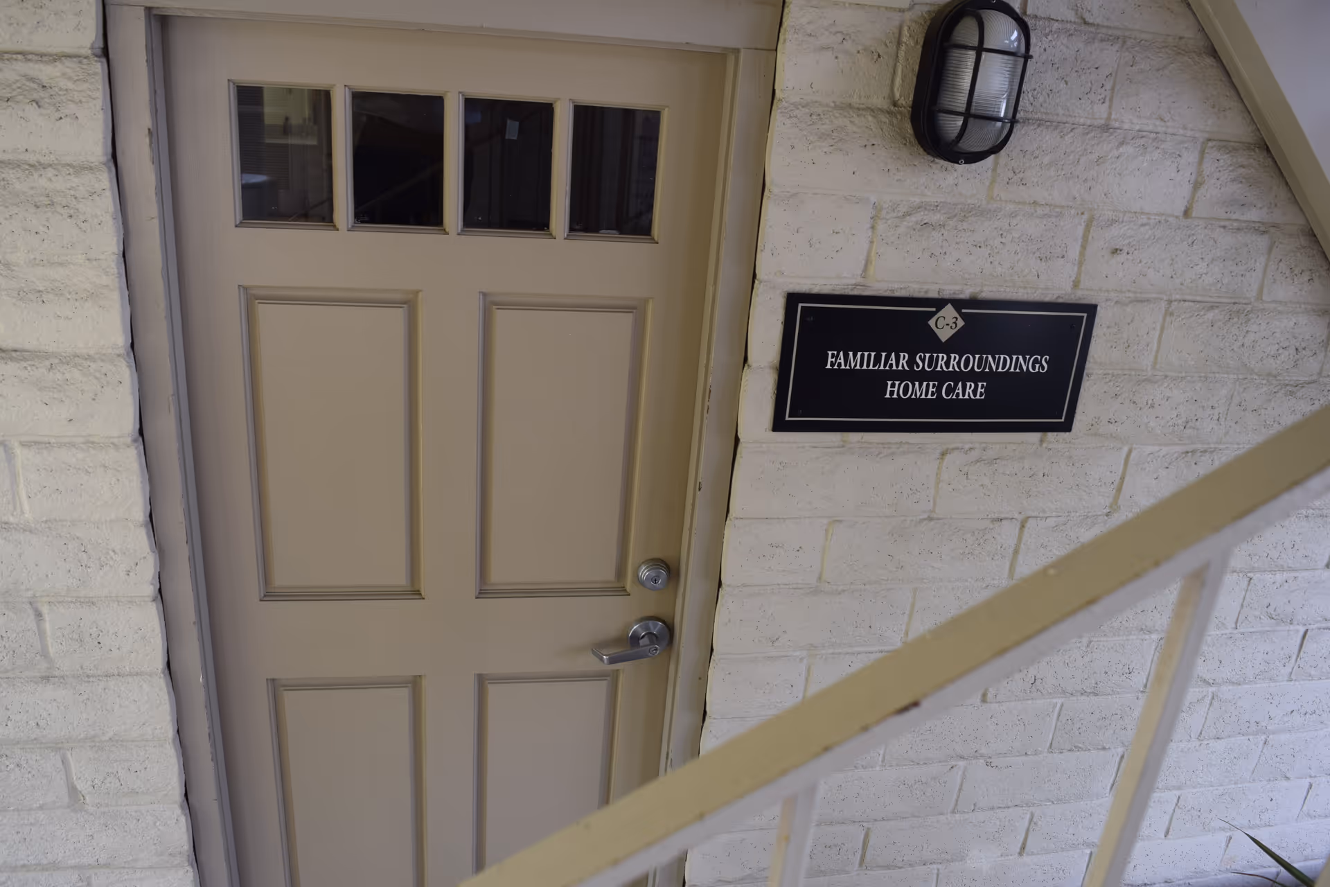 Beige exterior door beside a sign reading Familiar Surroundings Home Care.