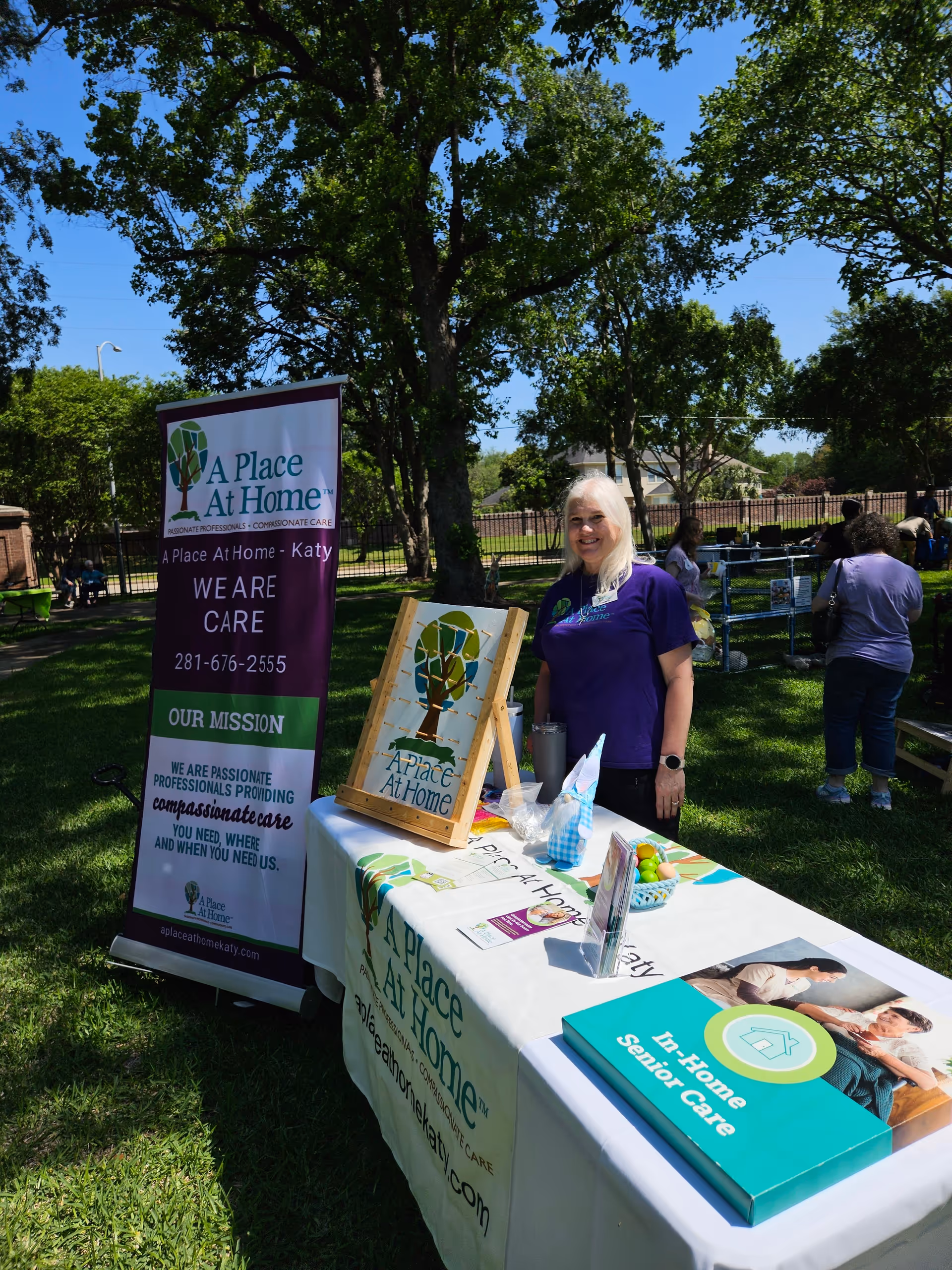 Outdoor information booth for A Place At Home Katy with a smiling staff member.