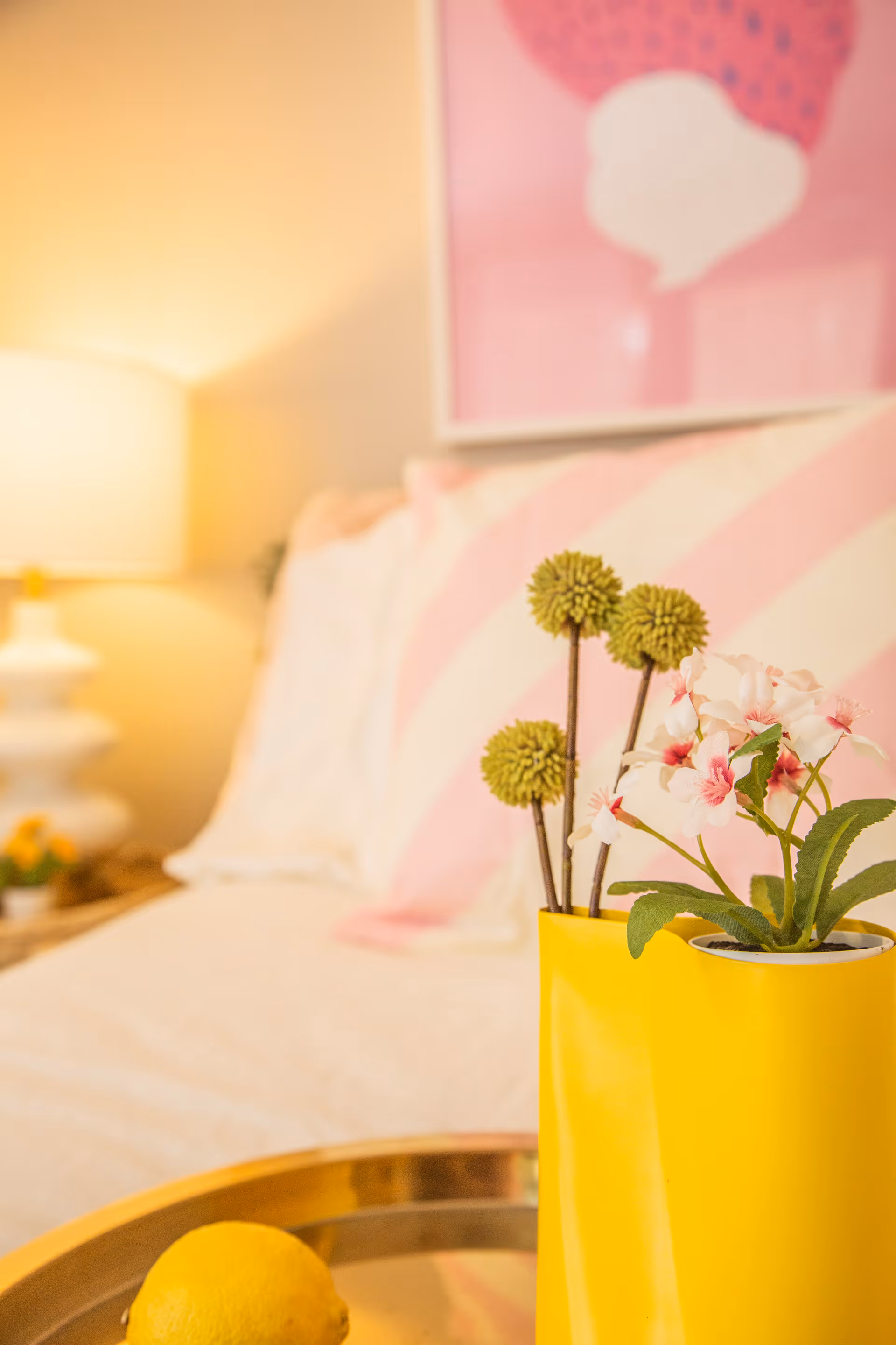 Cozy bedroom scene with a yellow vase of flowers on a tray by the bed.