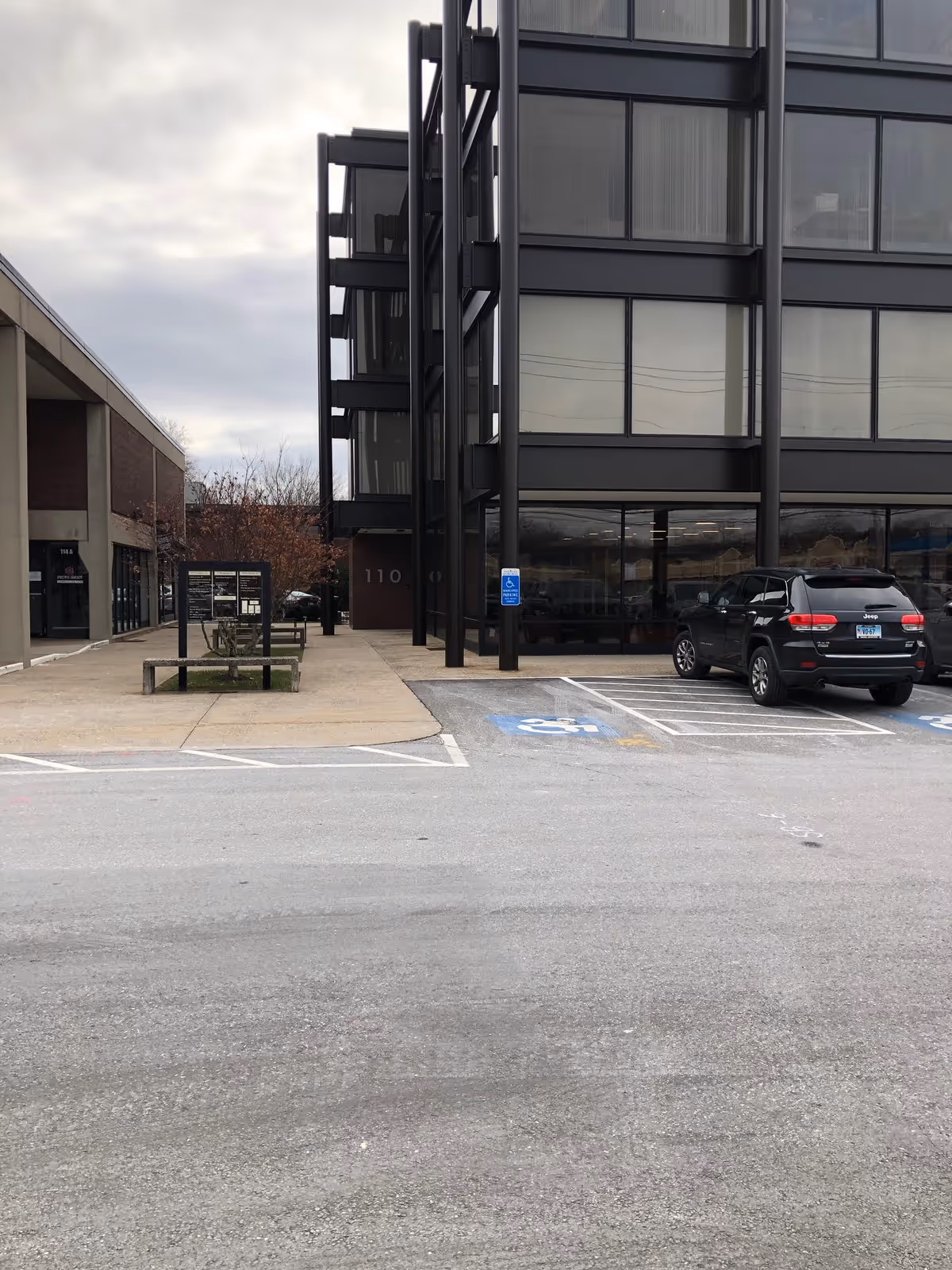Modern multi-story facility exterior with large windows, parking lot, and accessible entrance.