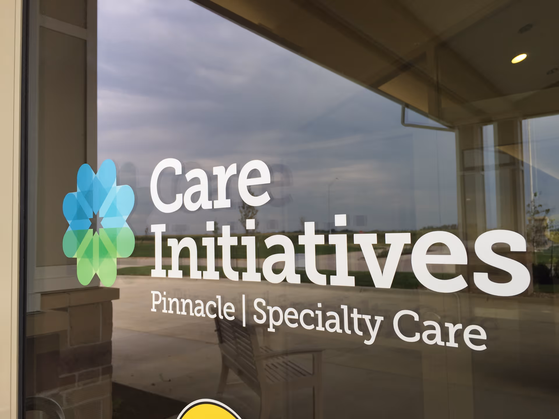 Glass entrance door displaying the "Care Initiatives Pinnacle | Specialty Care" logo and a multicolored floral emblem.
