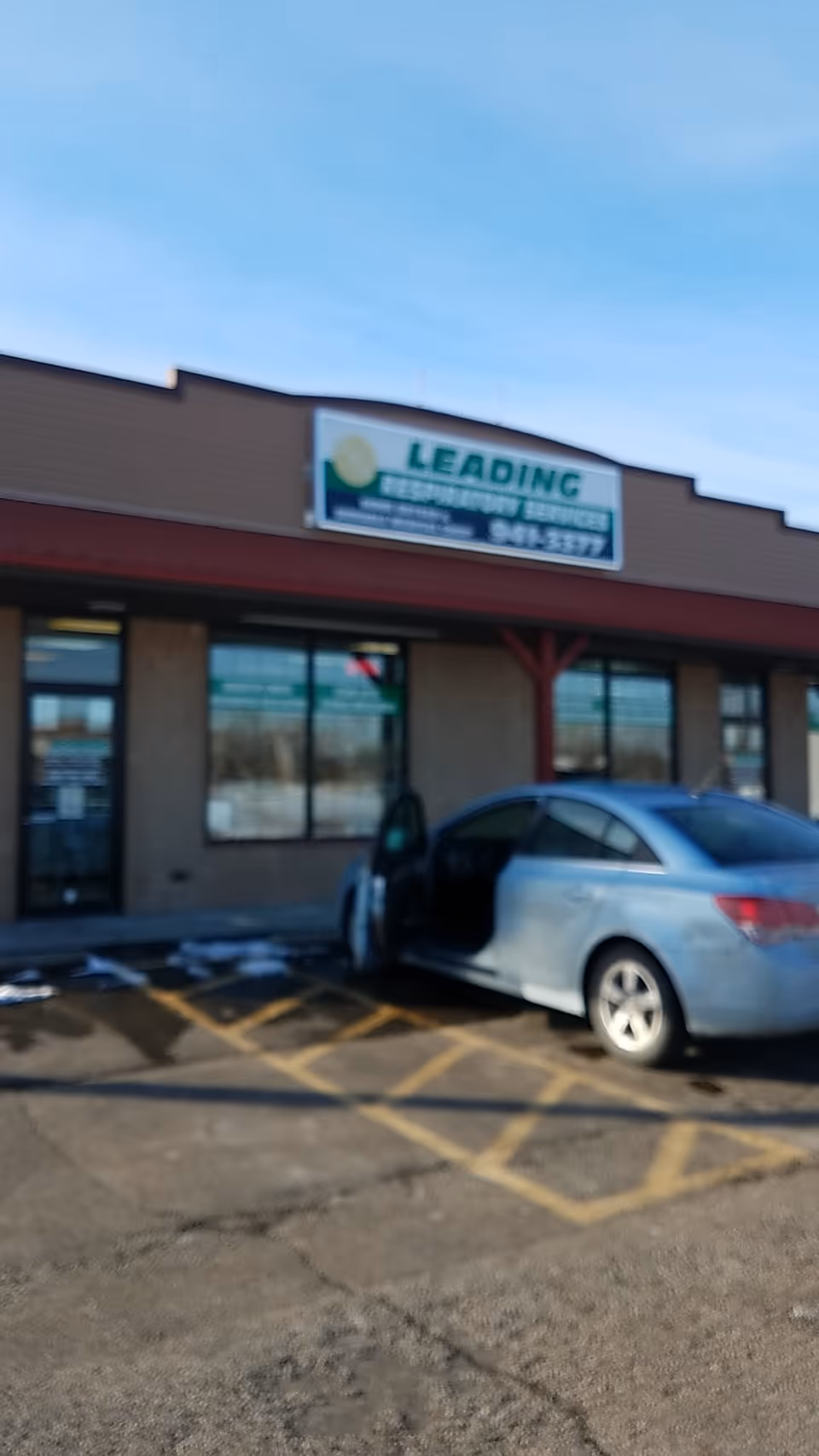 Exterior view of Leading Respiratory Services building with a blue car parked in front.