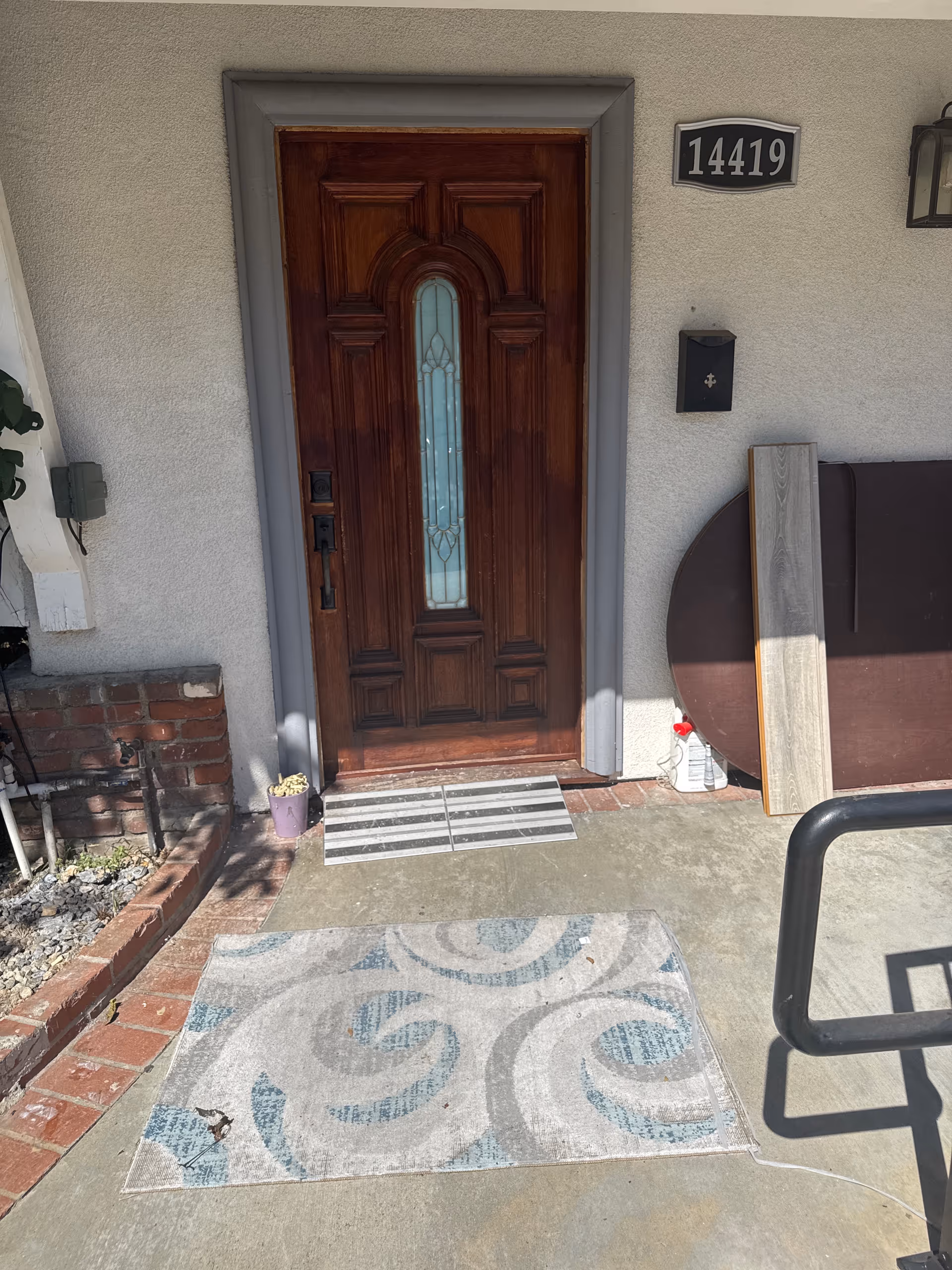 Wooden front door with glass panel, house number 14419, on a small porch.