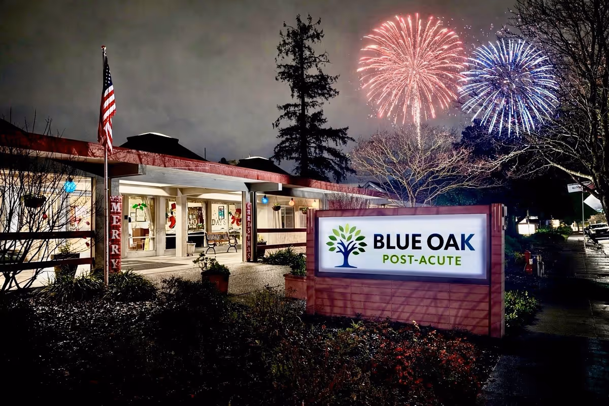 Night exterior of a single-story facility with a lit Blue Oak Post-Acute sign and fireworks.