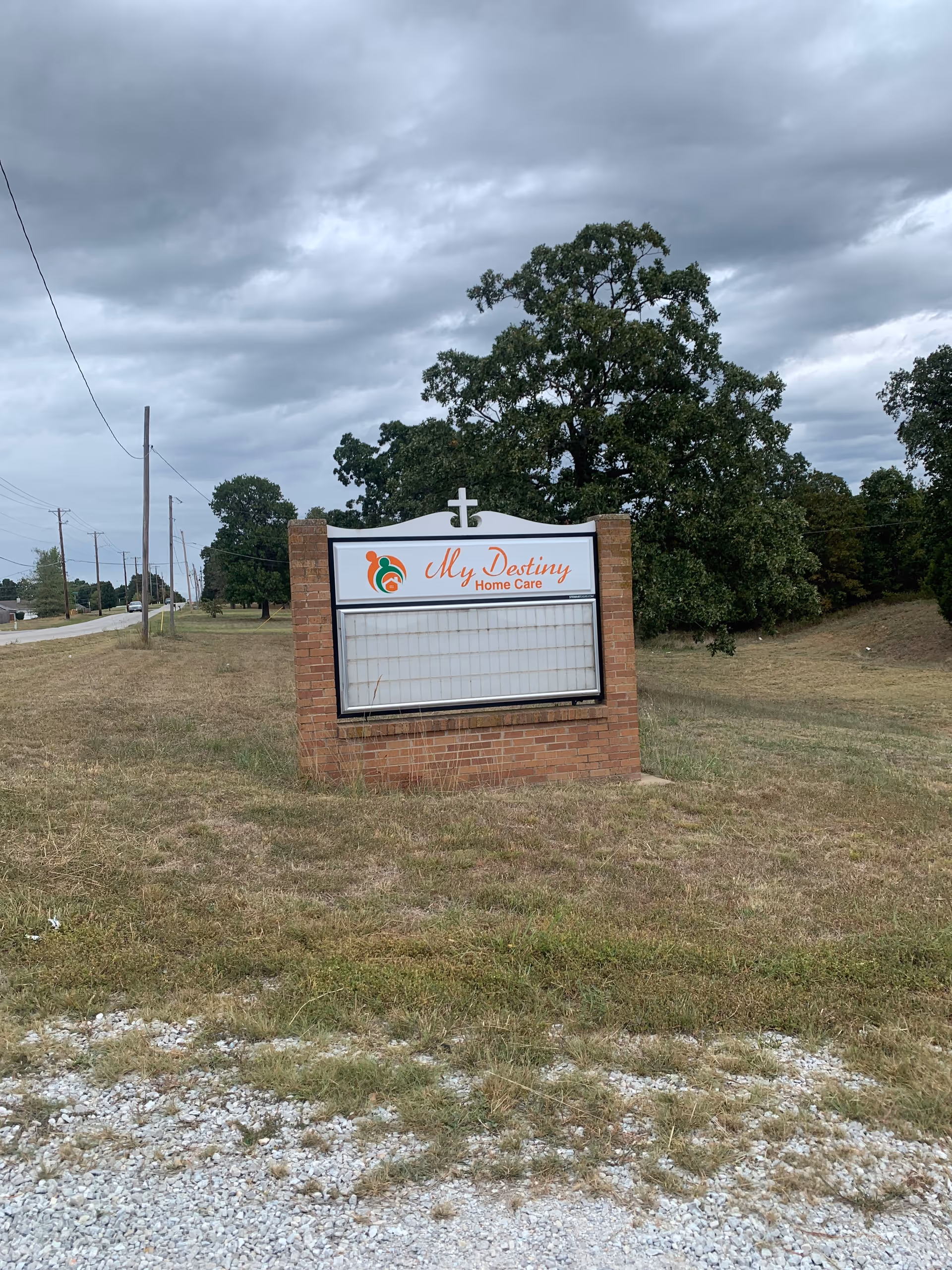 Exterior brick sign for My Destiny Home Care beside a road and trees