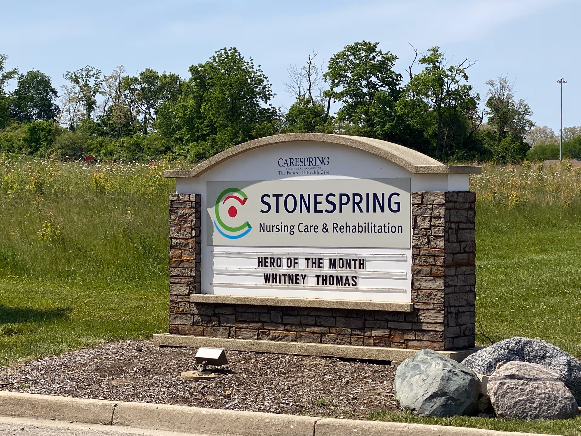 Outdoor stone sign for Stonespring Nursing Care and Rehabilitation in a grassy lot.