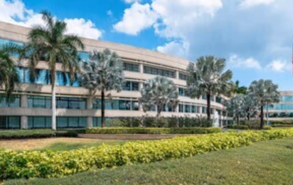 Modern multi-story facility exterior with palm trees and manicured landscaping.