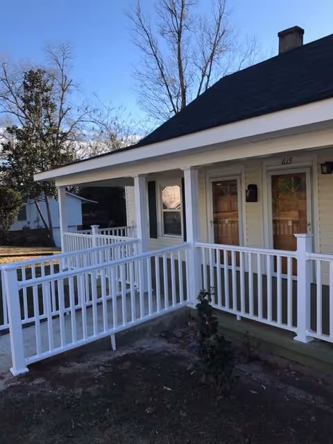Front exterior of a light-colored senior care home with white railing and porch.