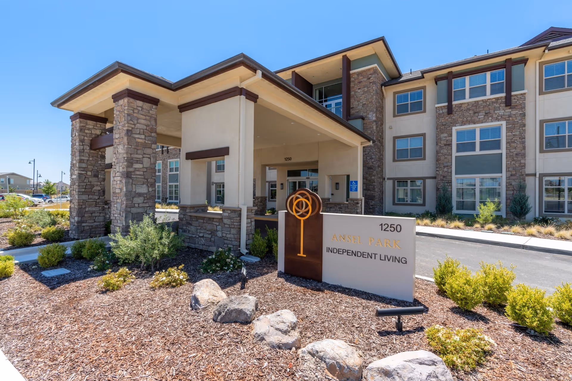 Exterior view of Ansel Park Independent Living entrance with stone columns and landscaped frontage.
