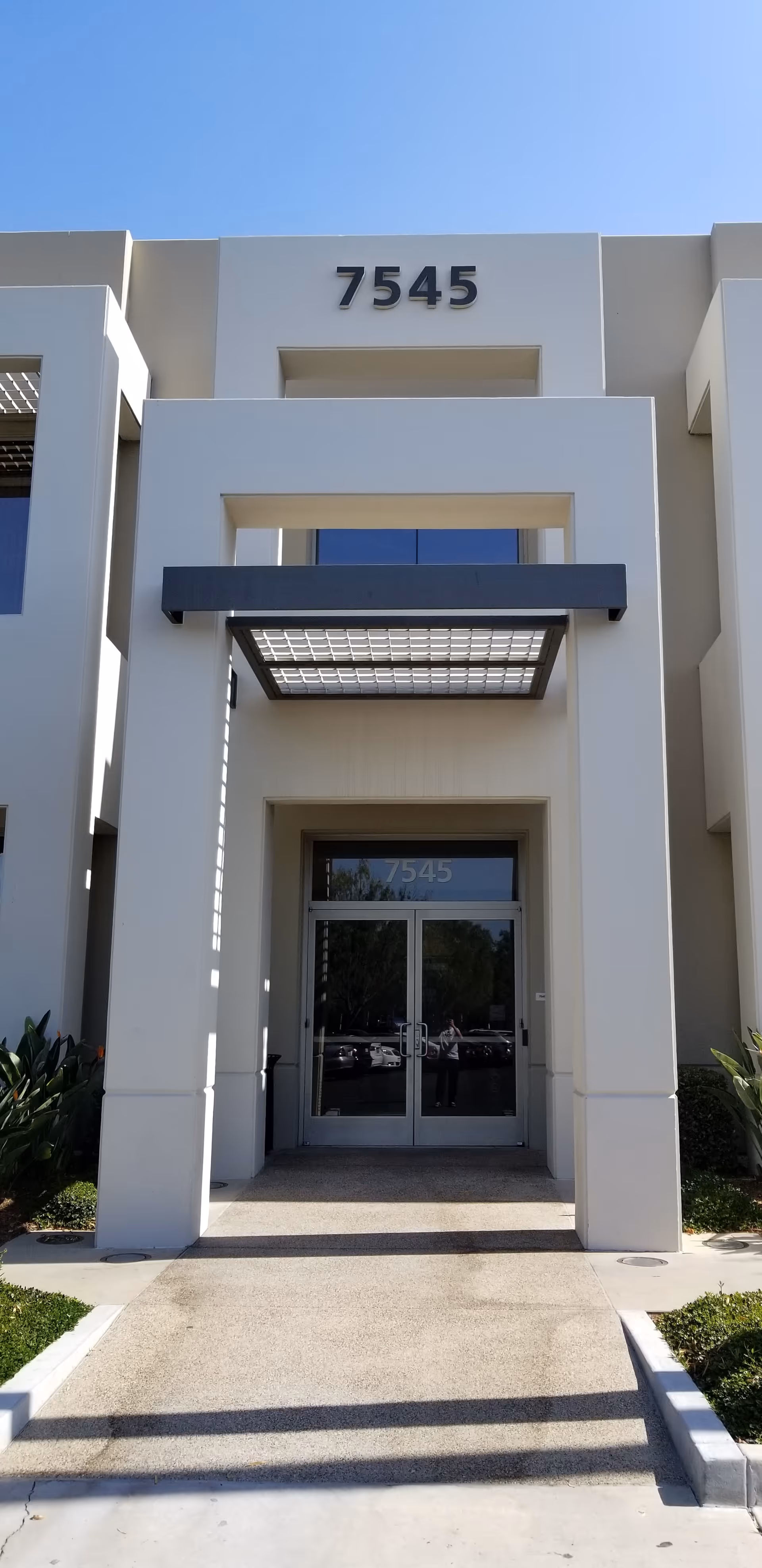 Exterior of a modern building entrance with the number 7545 above the doors
