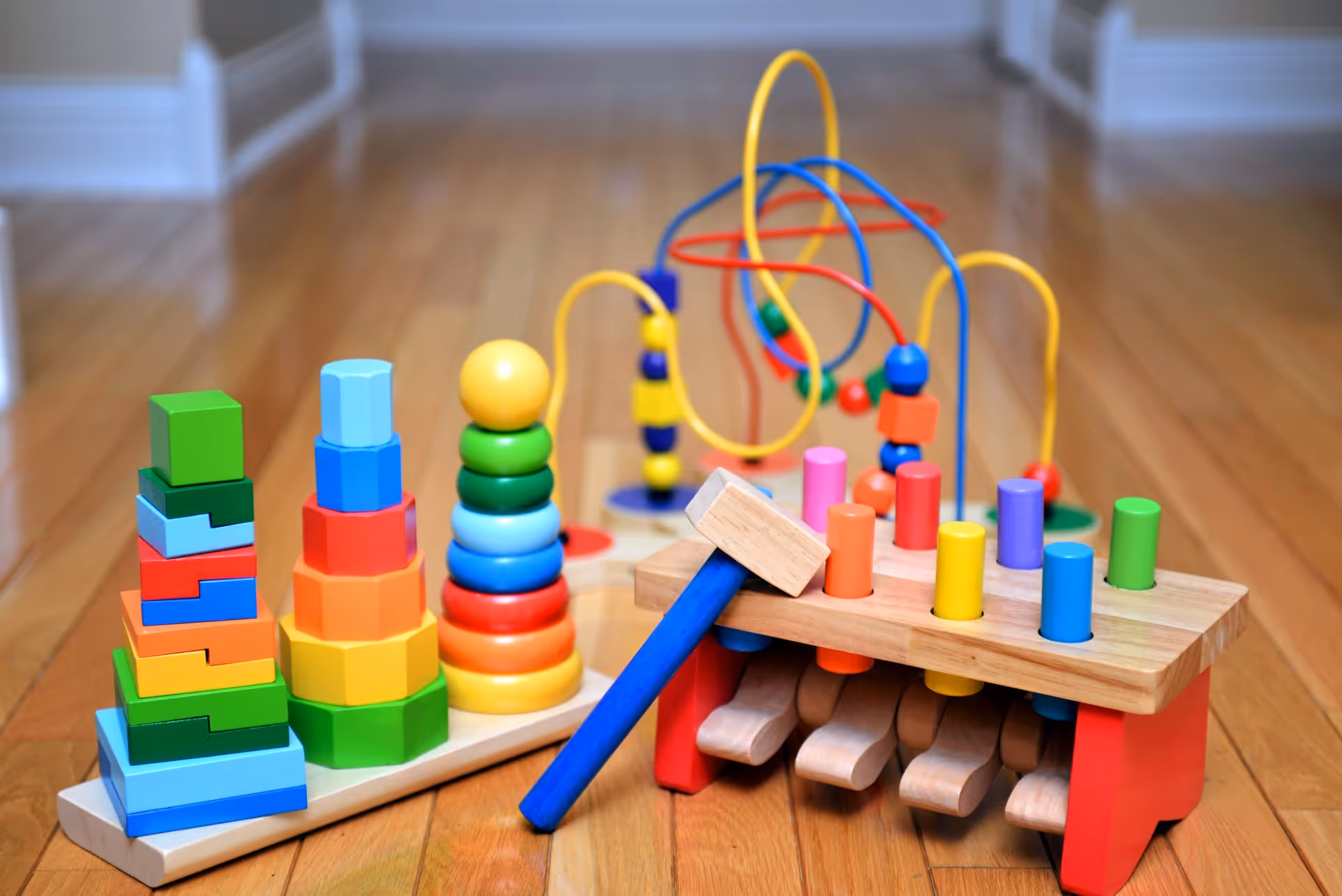 Colorful wooden toys and bead maze on a polished wooden floor.