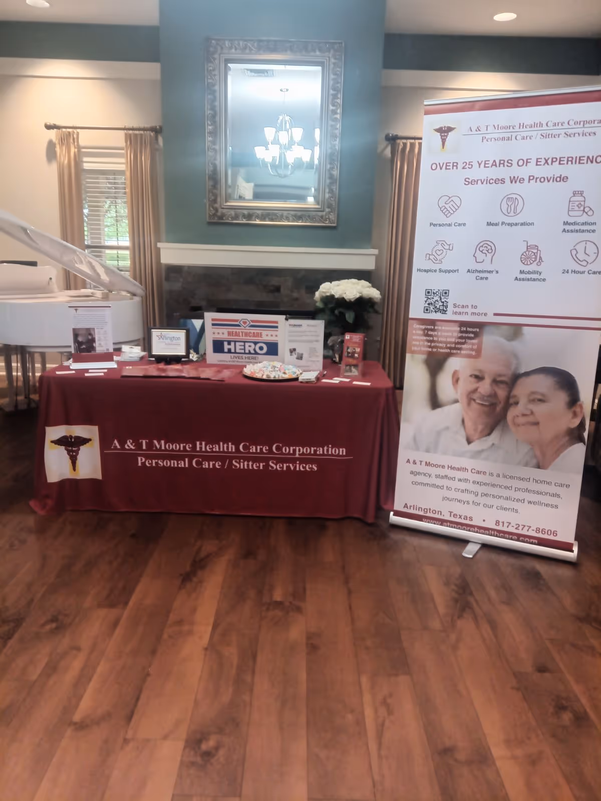 Indoor reception table with maroon tablecloth and banner for A and T Moore Health Care.