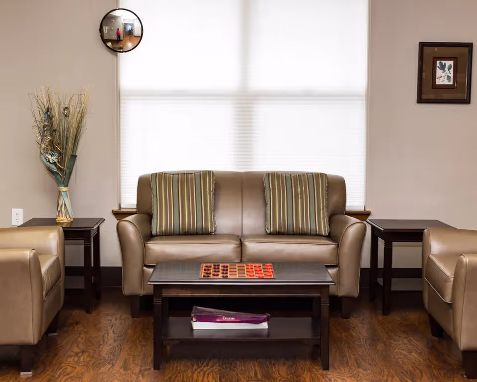 Cozy living room in Evergreen Court of Molalla with sofa, chairs, coffee table, and blinds.