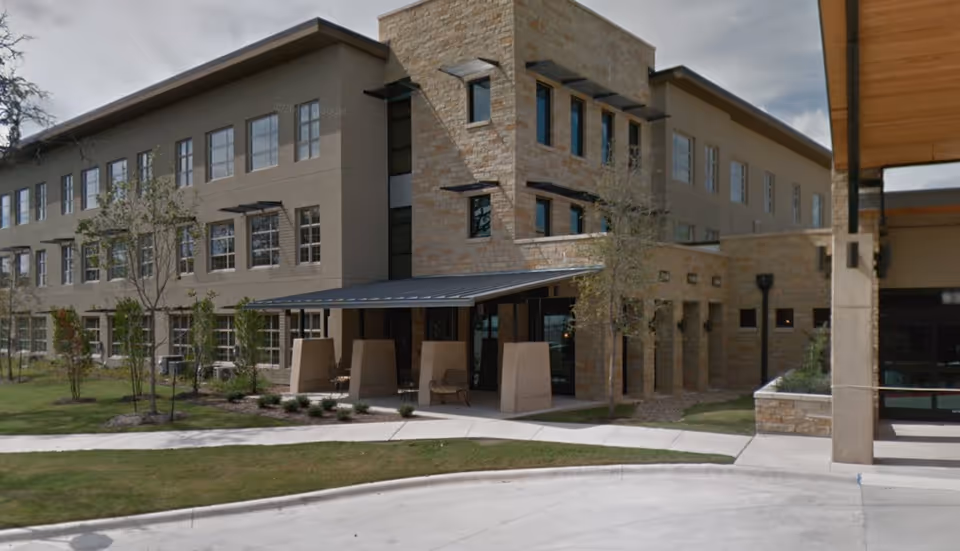 Modern multi-story senior living building exterior with stone accents and a covered entrance.