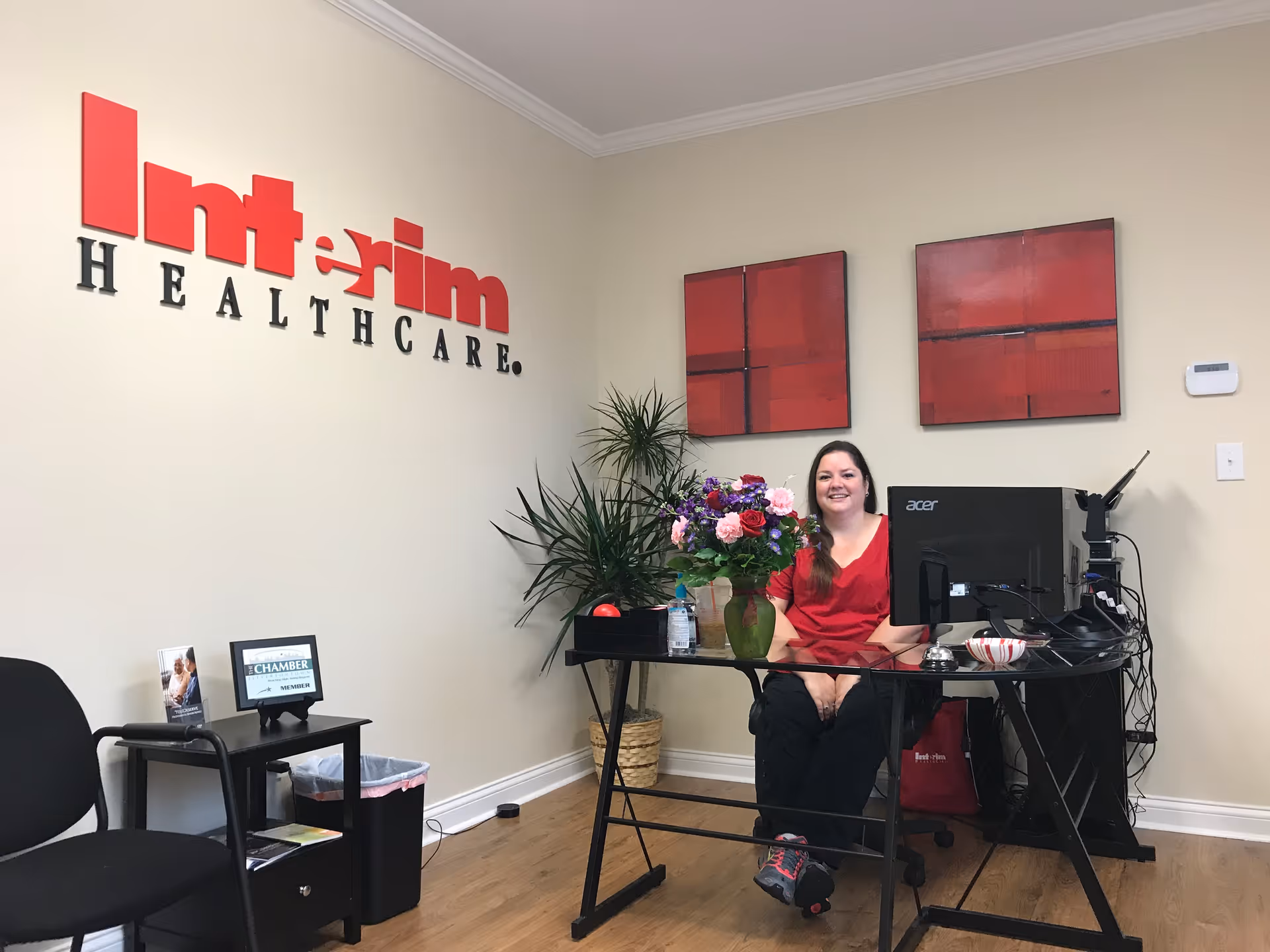 Reception area with a receptionist in red scrubs at a desk, by Interim HealthCare sign.