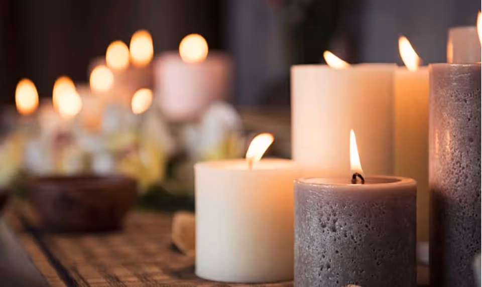 Close-up of several lit candles on a table with warm, soft background glow.