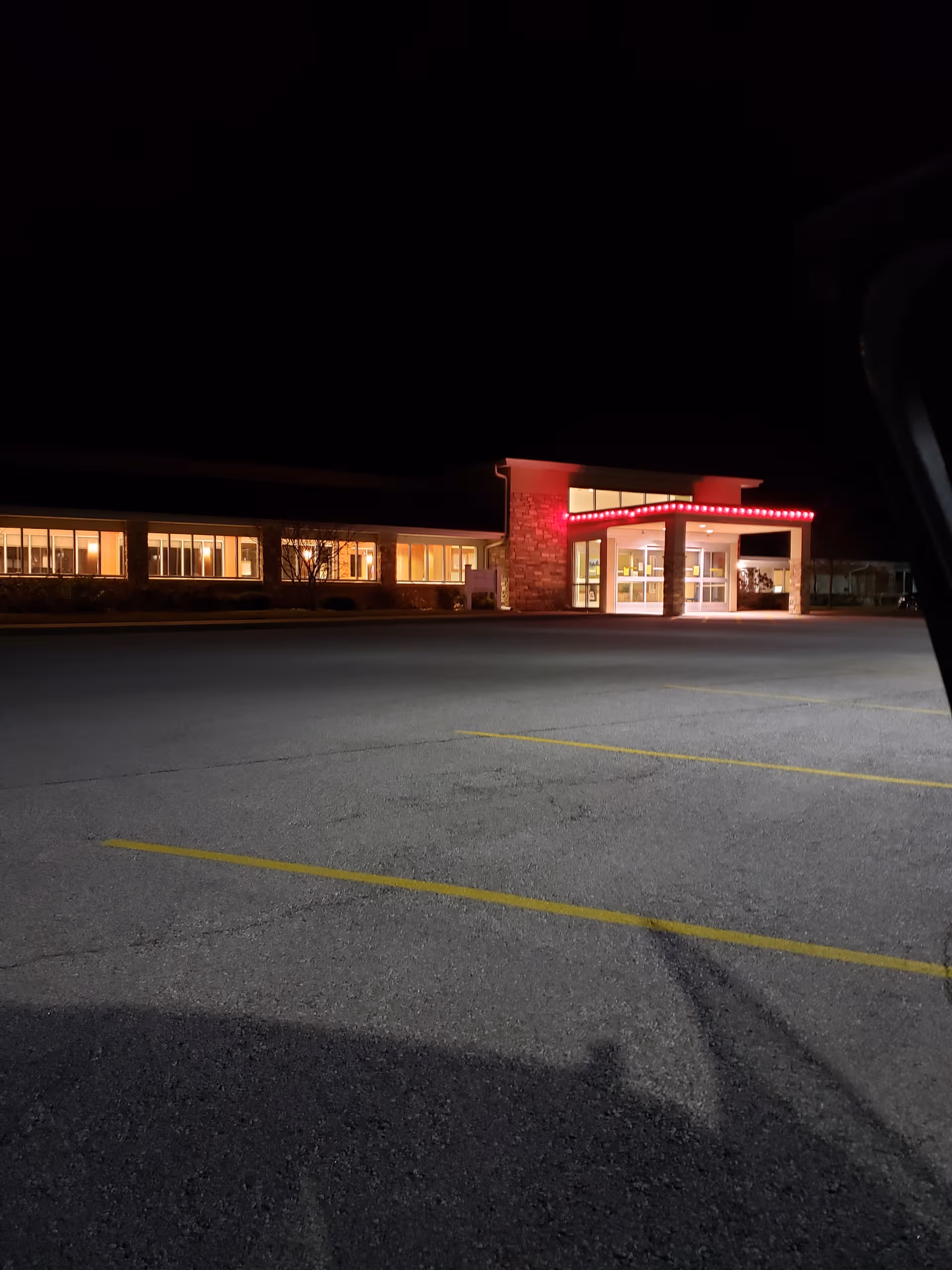 Nighttime exterior view of Lutheran Living building with lit entrance and vacant parking lot