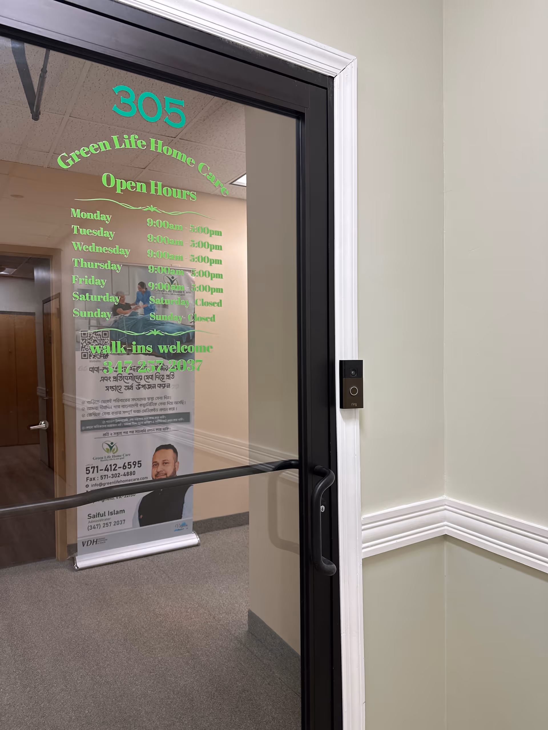 Glass door with Green Life Home Care signage showing hours inside a hallway.