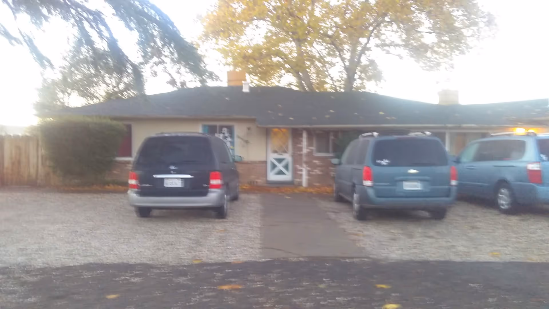 Sail House facility exterior, front view with a gravel parking area and several minivans.