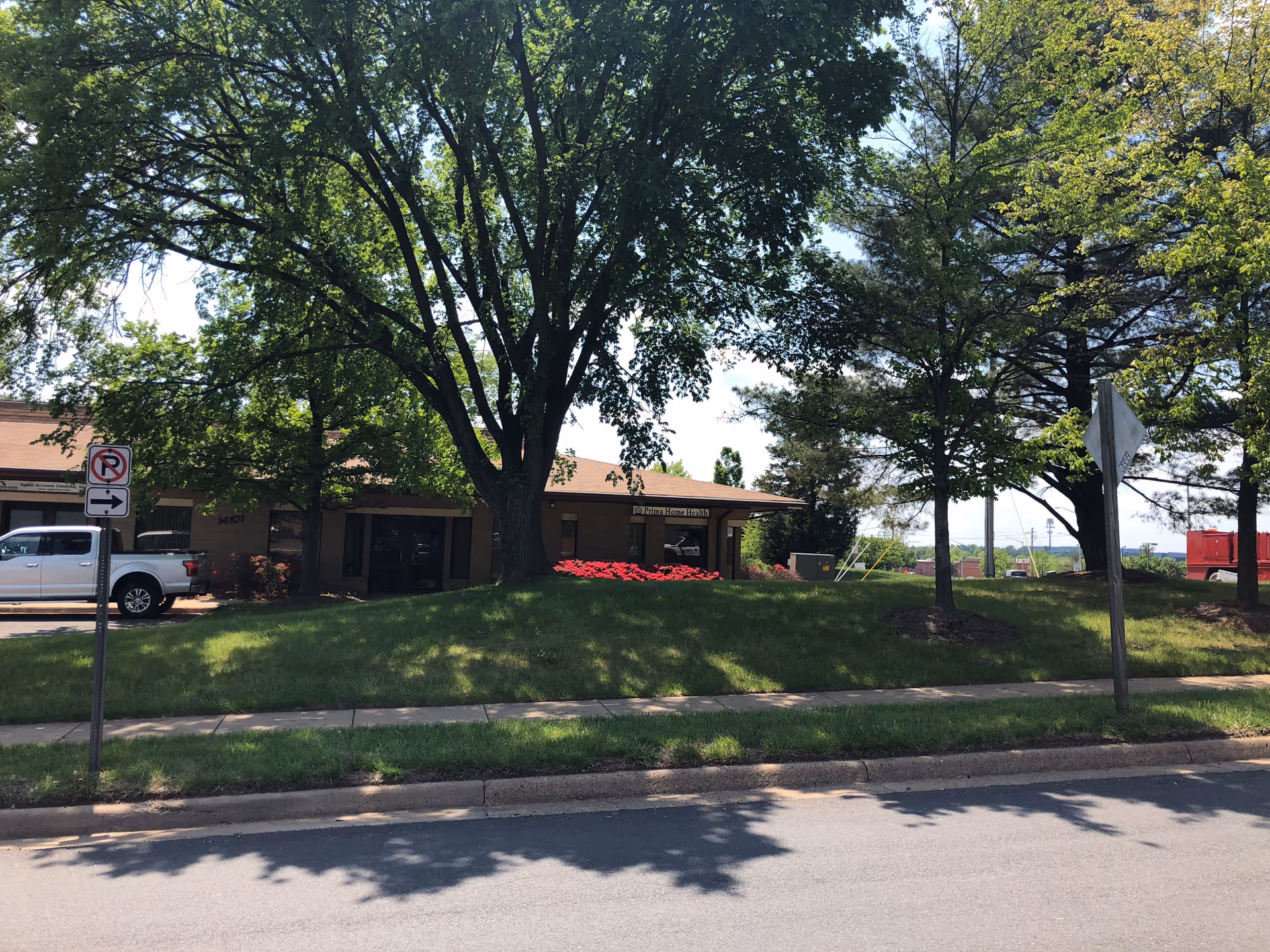 Exterior view of a single-story Prima Home Health, Inc building with trees, cars, and a lawn.