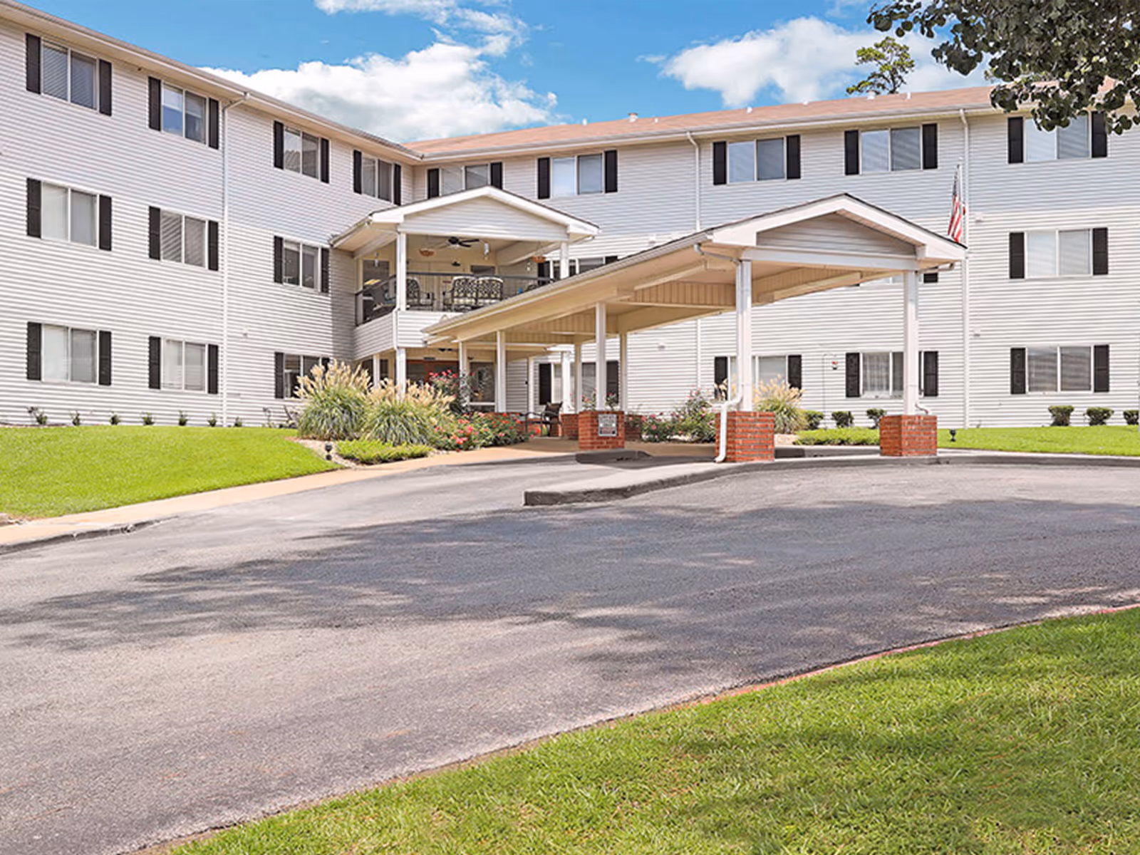 Exterior view of a white senior living building with a covered entrance.