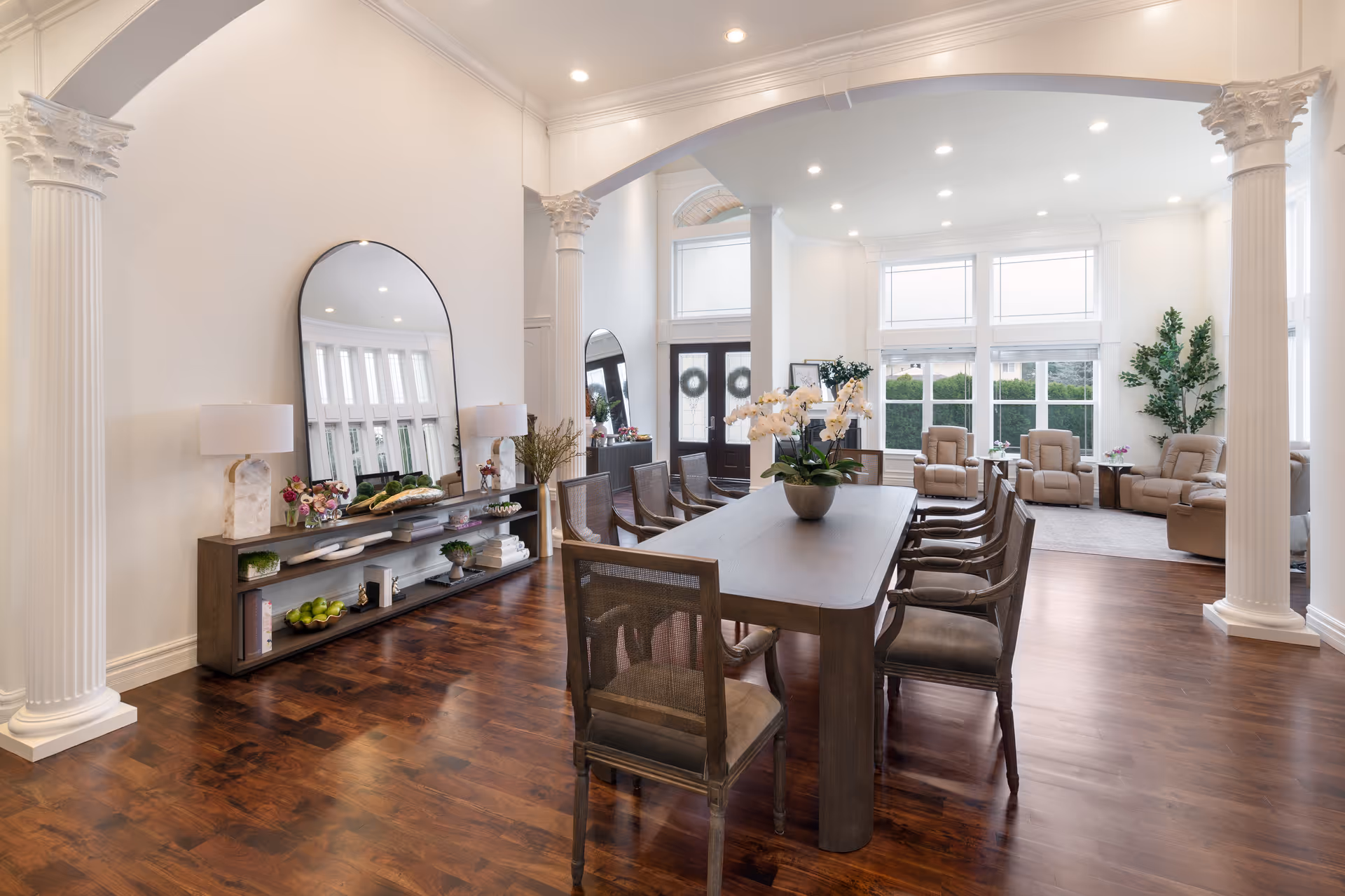 Bright dining room with a long table, chairs, and a seating area in back.