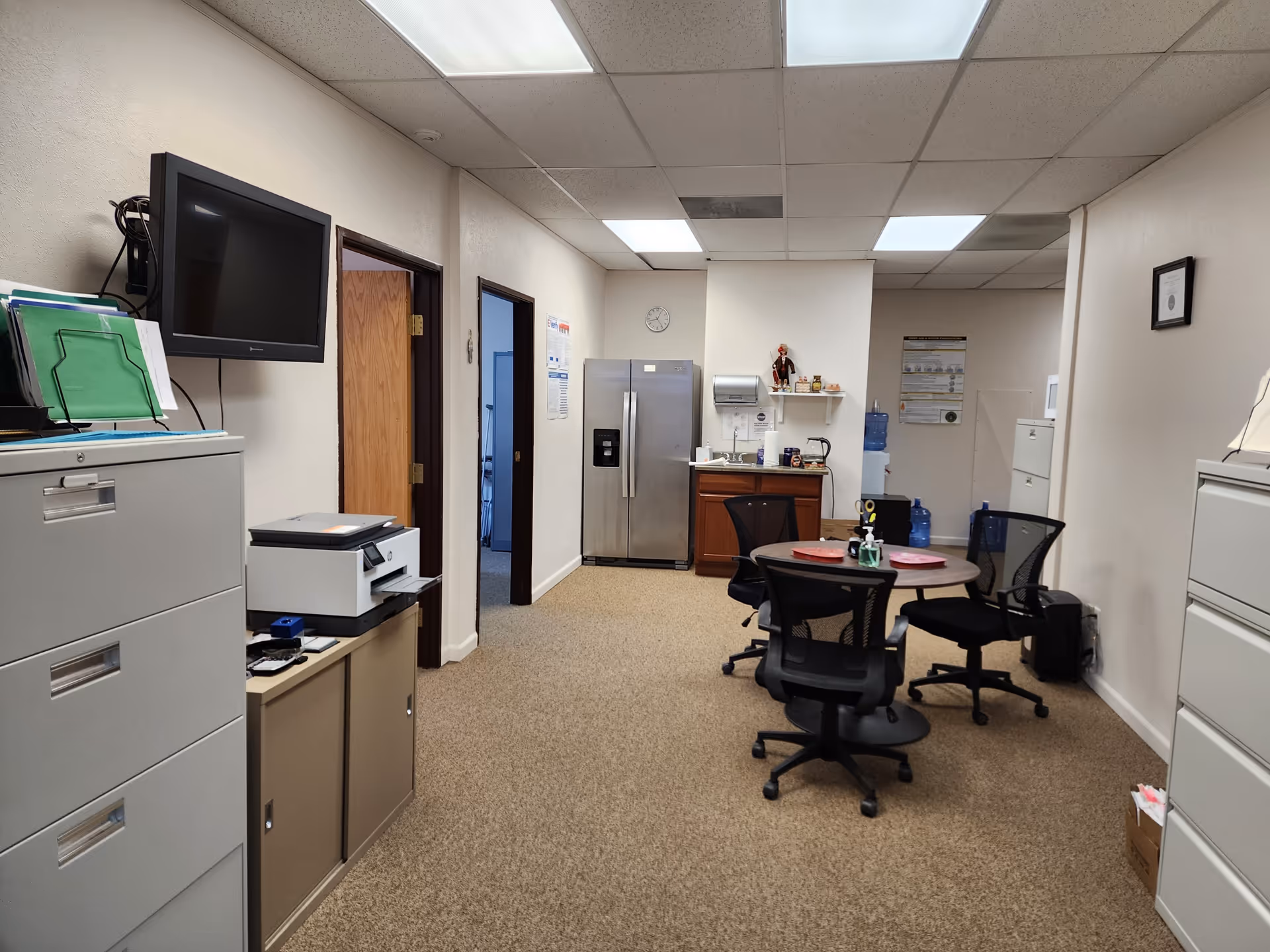 Office break room in a senior care facility with round table and filing cabinets.