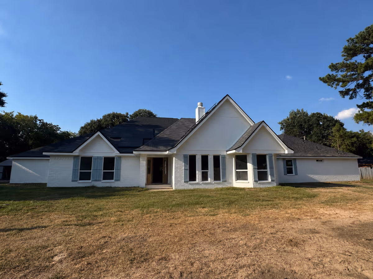 A single-story white building with a gabled roof and large front windows on a lawn.