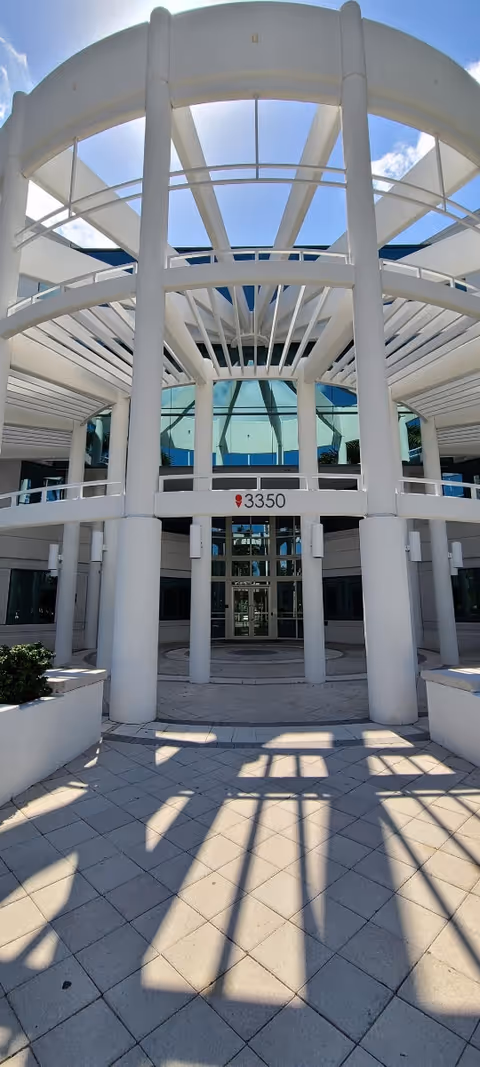Exterior of a modern white building entrance with tall columns and glass doors
