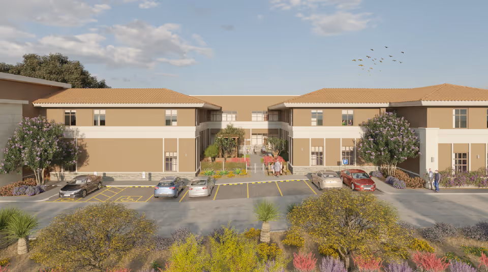Exterior view of The Retreat at Alameda: tan two-story building with central courtyard and parking.