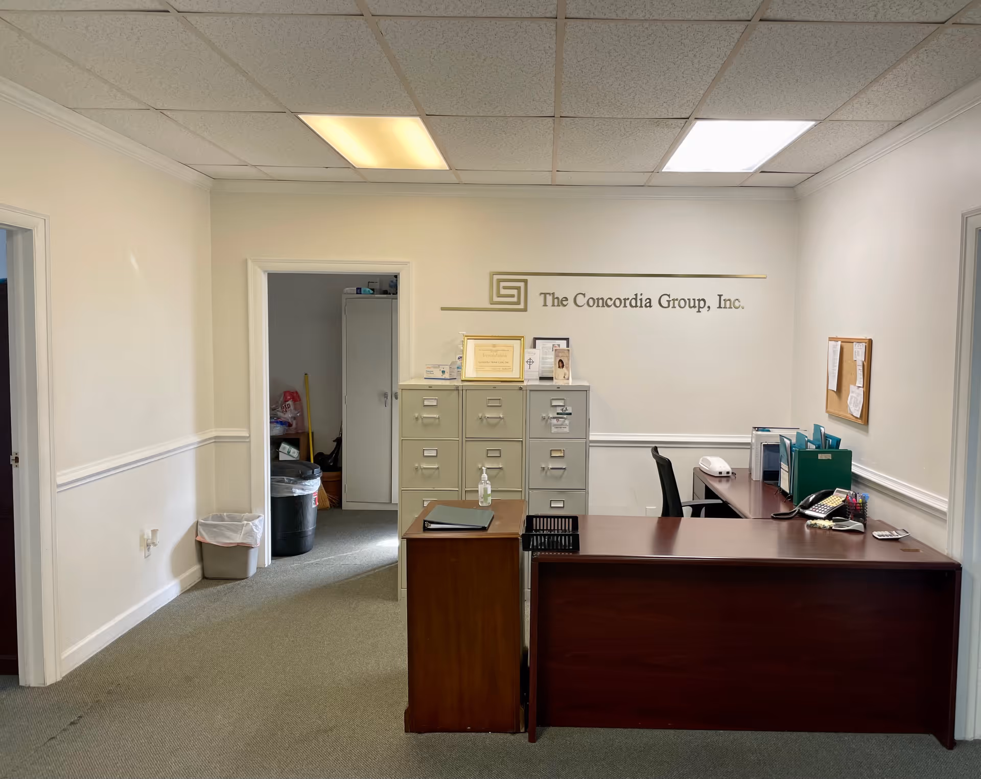 Office reception area with desk, filing cabinets, and a wall sign reading The Concordia Group, Inc.
