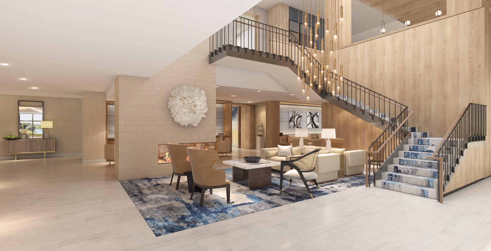 Modern senior living lobby with seating area, fireplace, rug and a sweeping staircase with pendant lights.