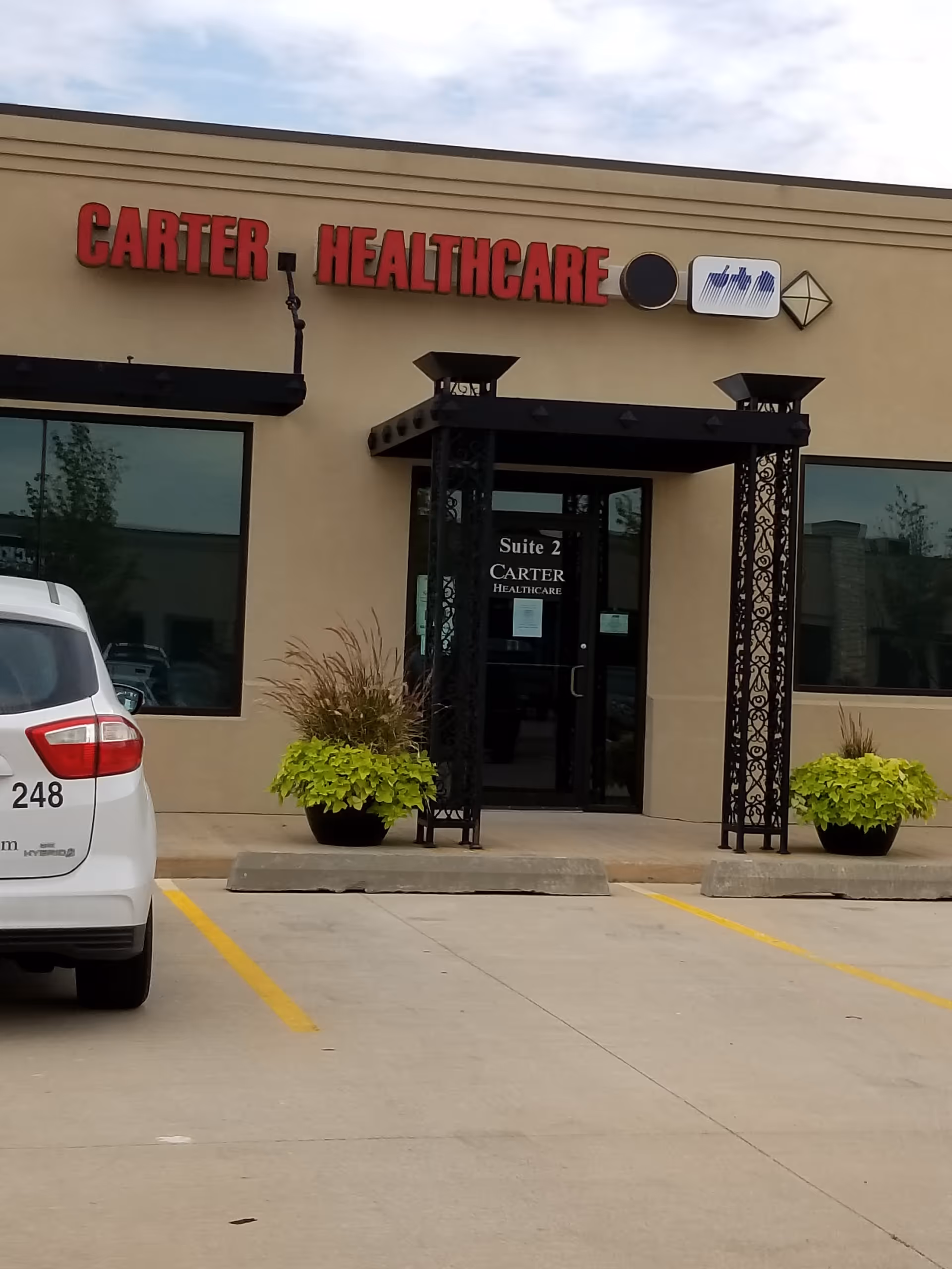 Exterior view of Carter Healthcare building with signage, entrance doors, and parked car nearby.