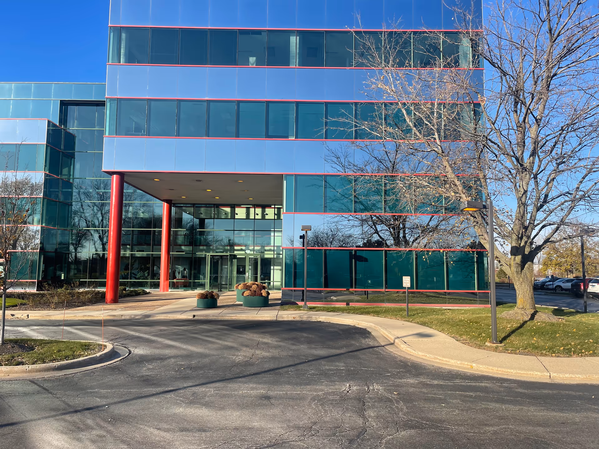 Mafolux Healthcare Services building with glass facade, red columns, and parking.