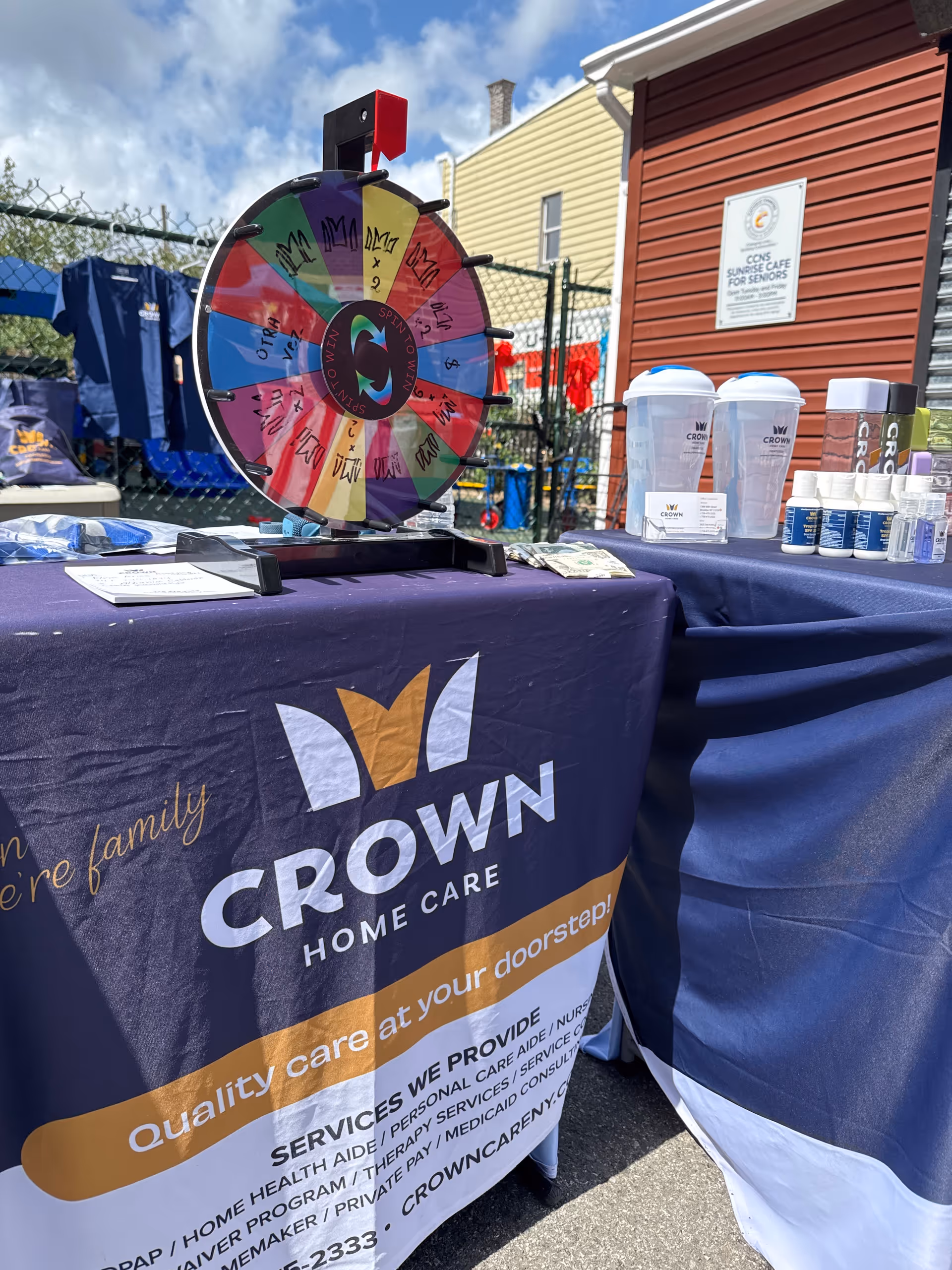 Spin wheel and promotional table for Crown Home Care outdoors at an event.