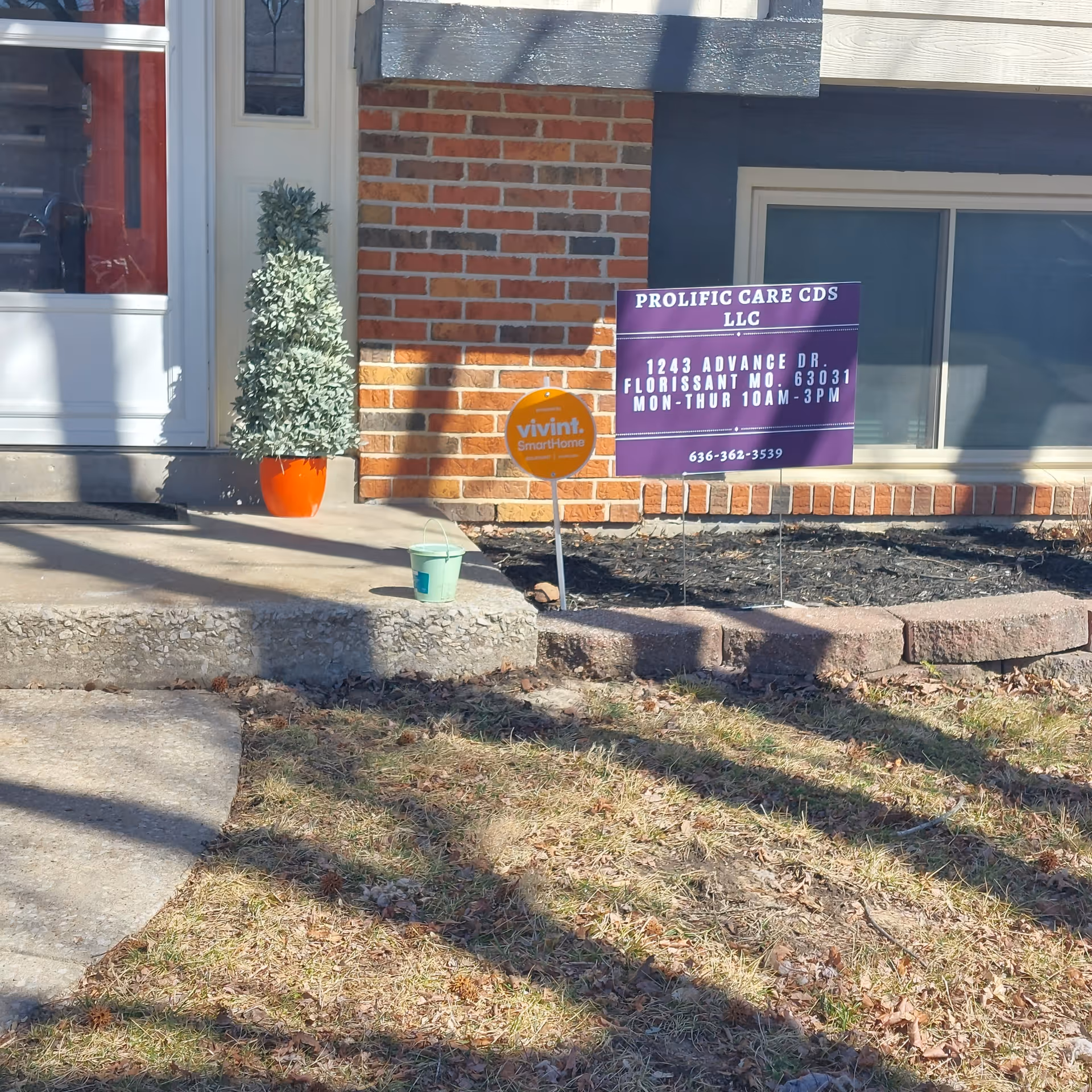 Exterior view of a brick building with a Prolific Care sign and orange planters.