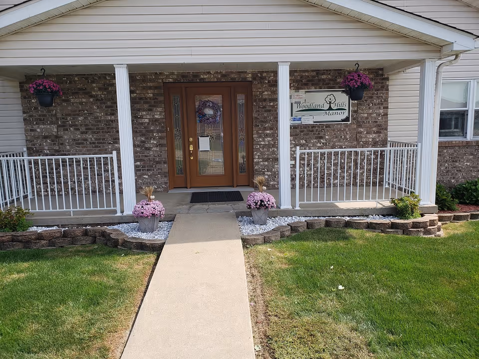 Entrance to Woodland Hills Manor, brick exterior with a porch and hanging flower baskets.
