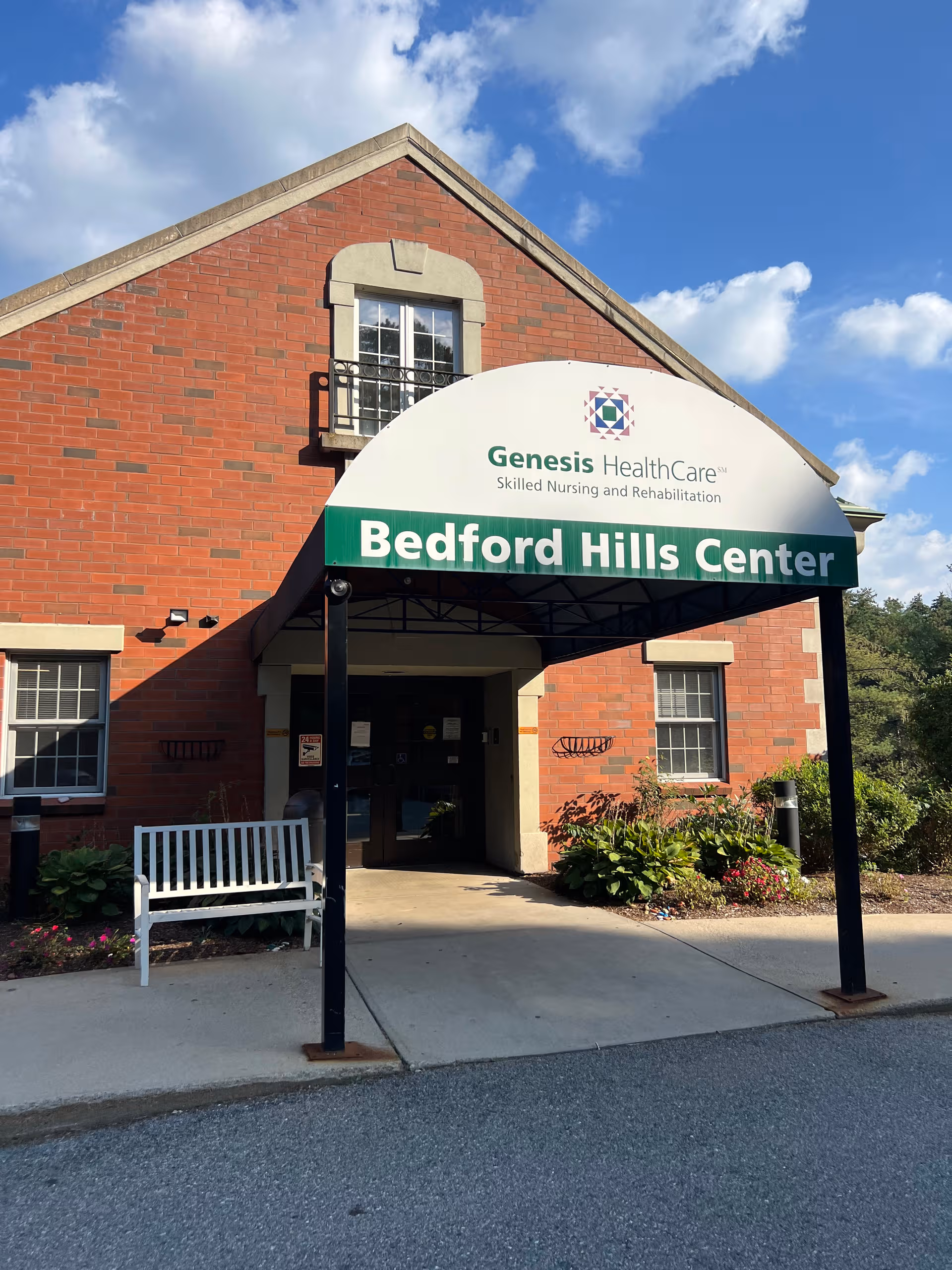 Brick building with curved white and green Bedford Hills Center sign over entrance.