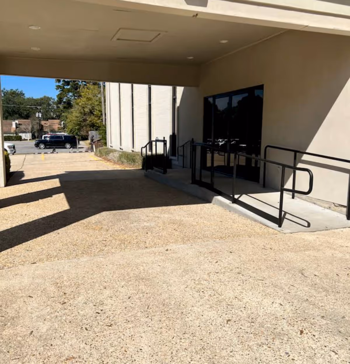 Exterior entrance of a beige building with a ramp and black handrails