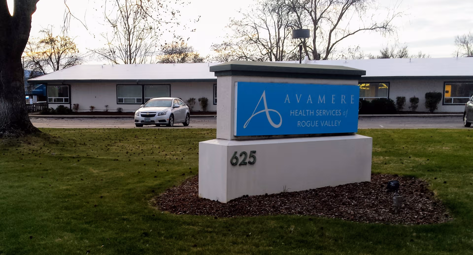 Exterior view showing Avamere Health Services sign, building frontage, and a parked car.