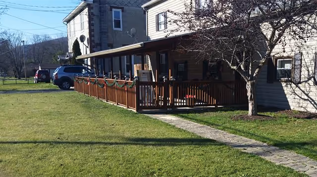 Exterior view of Chamberlain Graceful Living, a senior facility, with a wooden front porch and lawn.