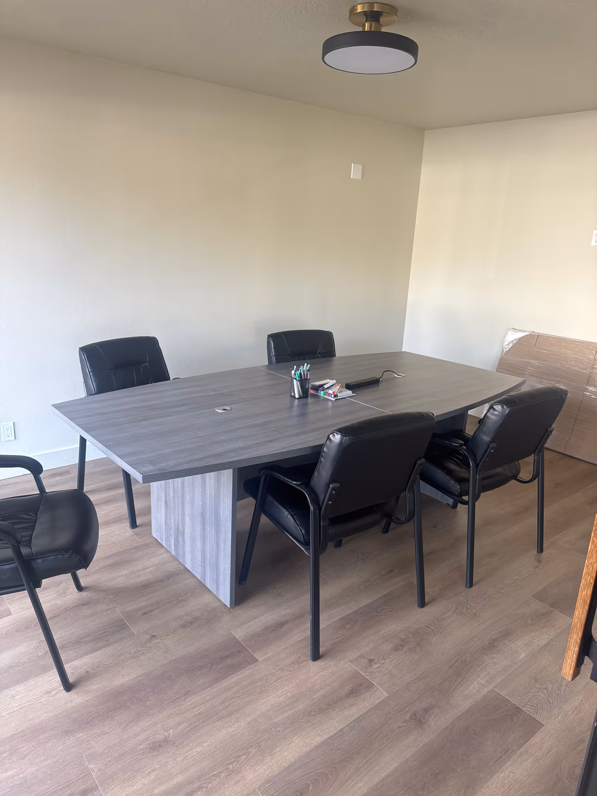 A modern meeting room with a large table and six black chairs.