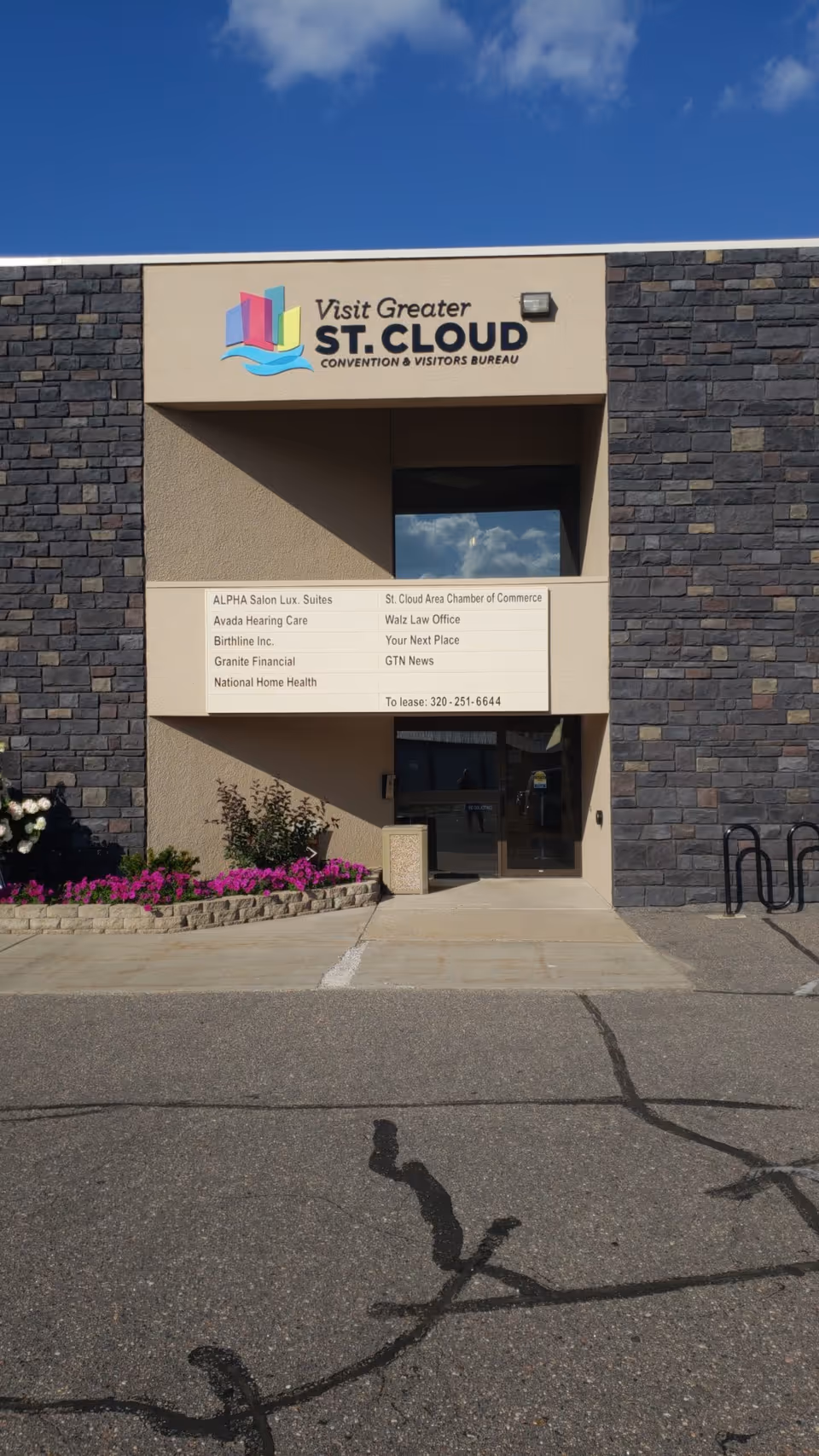 Exterior stone facade with entrance, National Home Health signboard, and flowers.