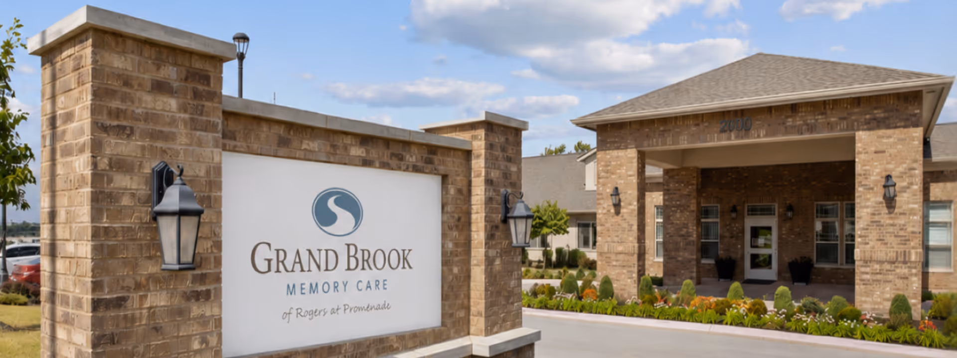 Brick entrance with a Grand Brook Memory Care sign and manicured landscaping.